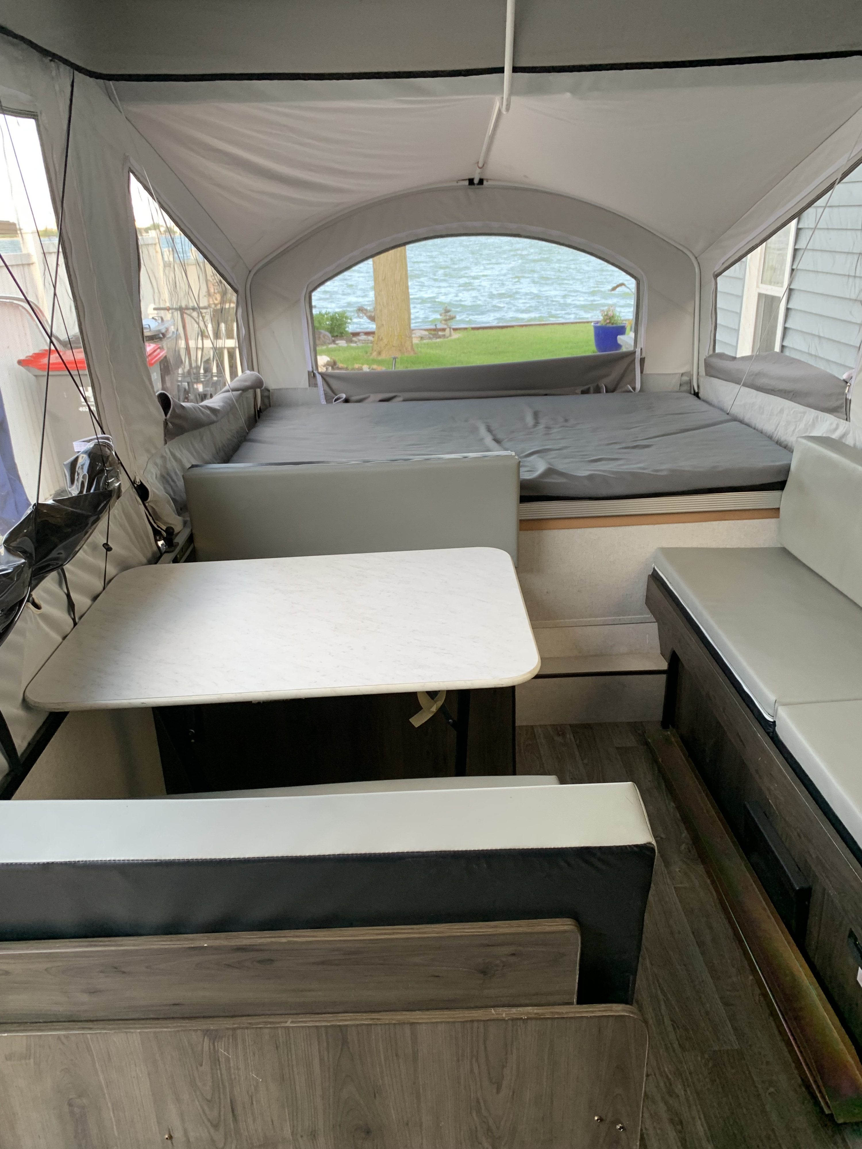 Cozy pop-up camper interior with a lake view, featuring dining area and bed, perfect for your next RV rental adventure.. Coachman Clipper 2021