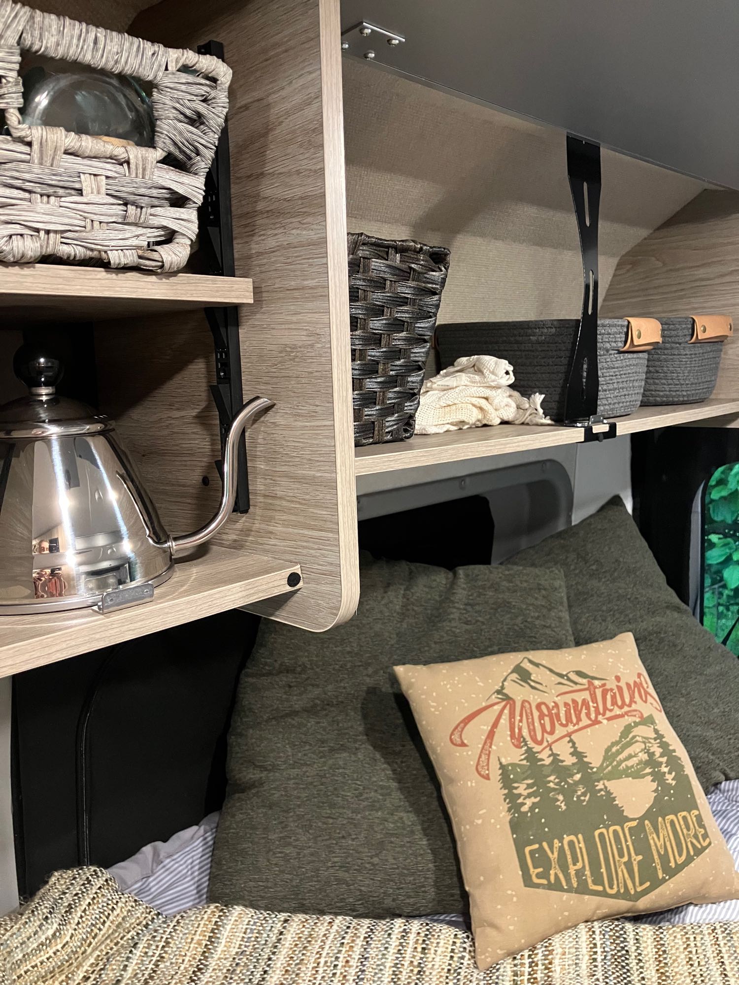 RV rental showing organized shelves, baskets, a kettle, and a cozy bed with an "Explore More" pillow.. Winnebago Winnebago 2023