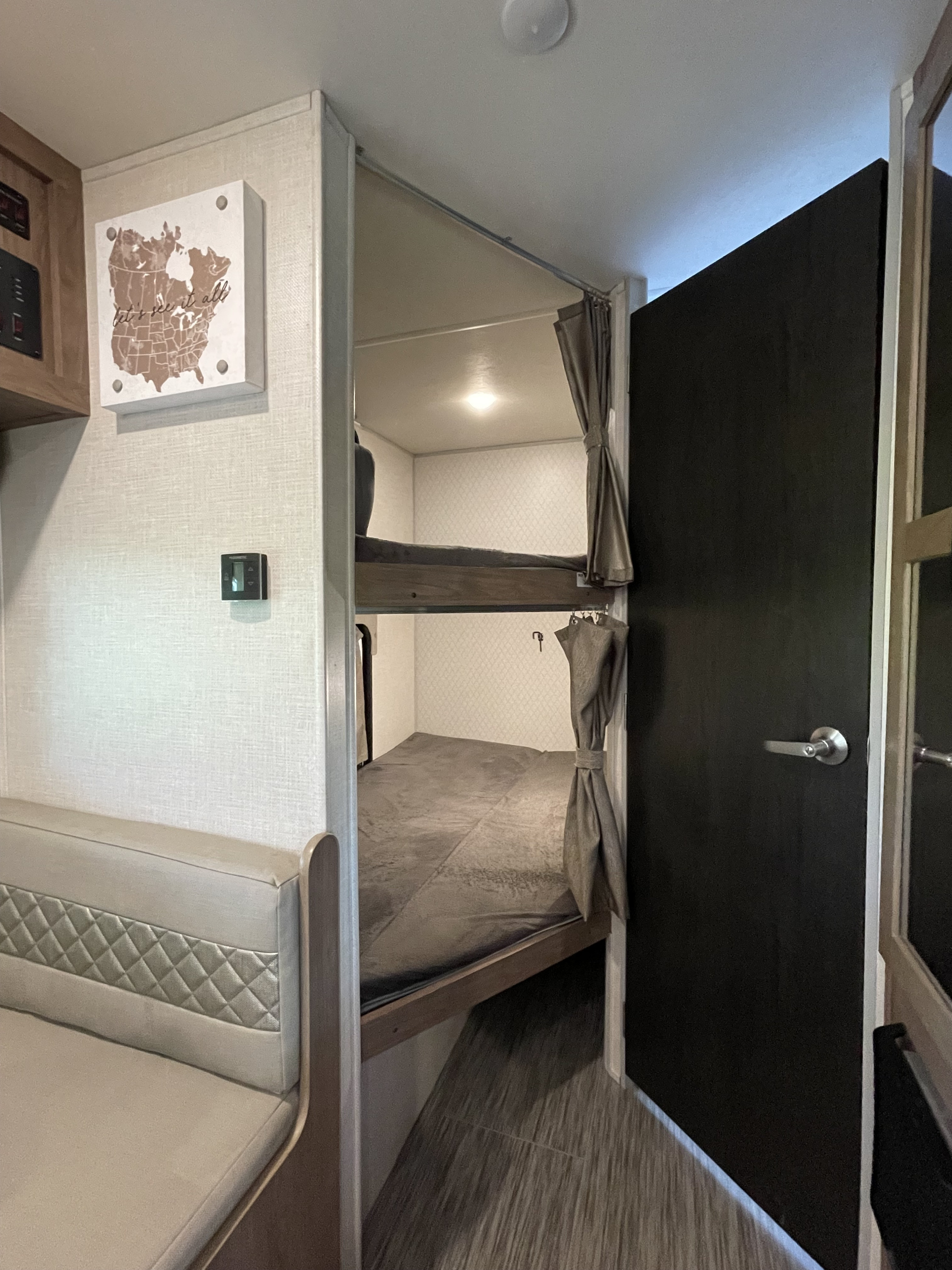 RV rental interior showing cozy bunk beds, a dinette, and wall controls. Ideal for family road trips.. Forest River No Boundary 2020
