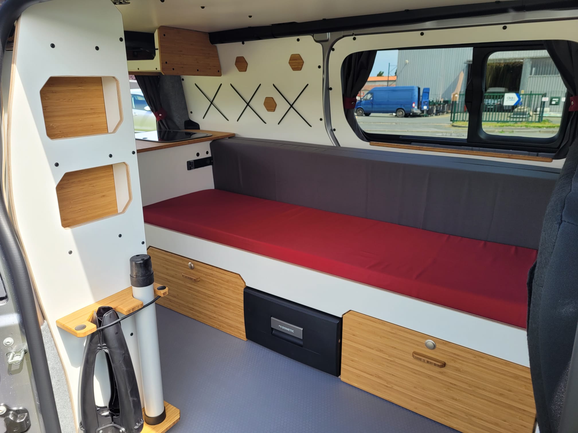 RV rental campervan's versatile interior: bed, Dometic fridge, bamboo storage, and shelving for comfortable mobile travel.. Opel VIVARO 2025