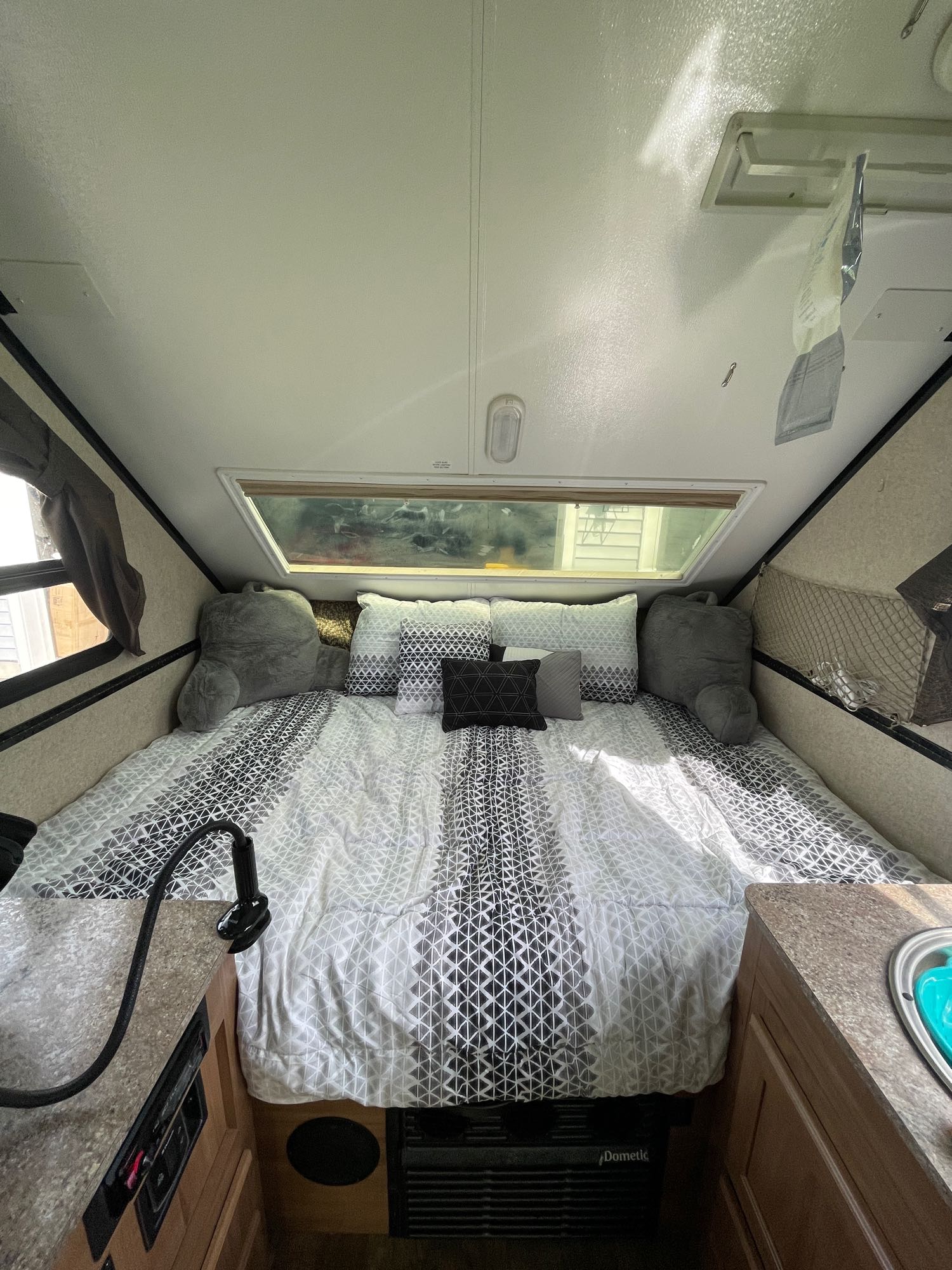 Cozy RV rental bedroom setup: patterned bed with pillows, large window, and compact counter space for comfortable travel.. Forest River Rockwood Premier 2018