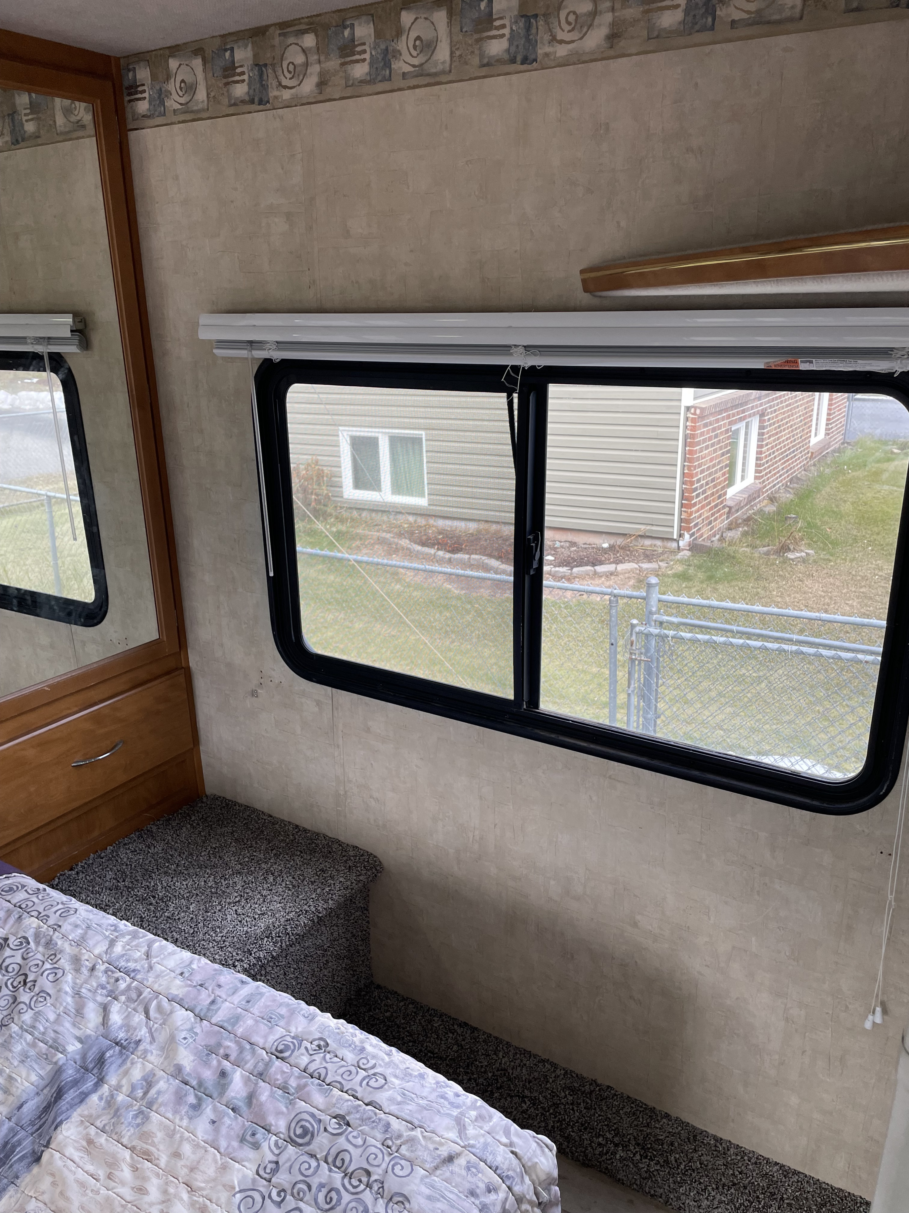 RV rental bedroom interior: light walls, cozy bed, built-in wooden dresser/mirror, and window with outdoor view.. Fleetwood Fiesta 2005