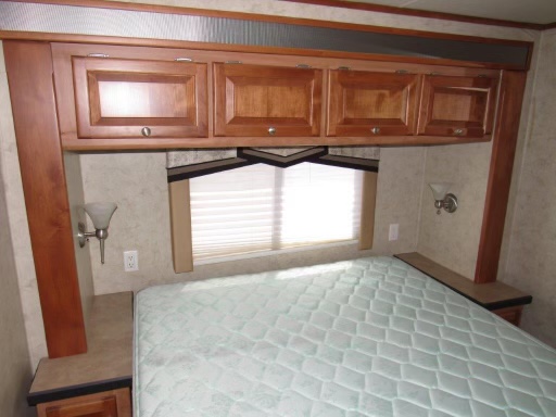 RV rental: A cozy bedroom with a quilted bed, overhead wood cabinets, and functional bedside tables & lamps. Perfect for rest.. Allegro Allegro Motorhome 2007
