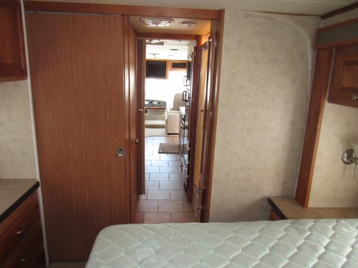 RV rental interior: A bedroom with mattress and cabinets, looking into a tiled hallway that leads to the main living area.. Allegro Allegro Motorhome 2007