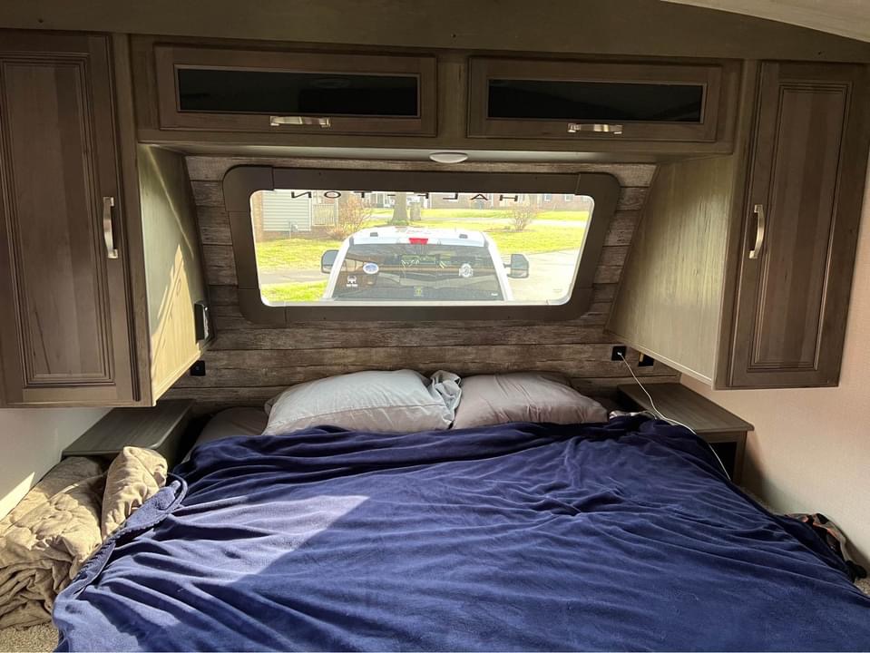 Cozy RV rental bedroom with a large bed, ample storage, and a window view of the outside.. Keystone RV Cougar 2022