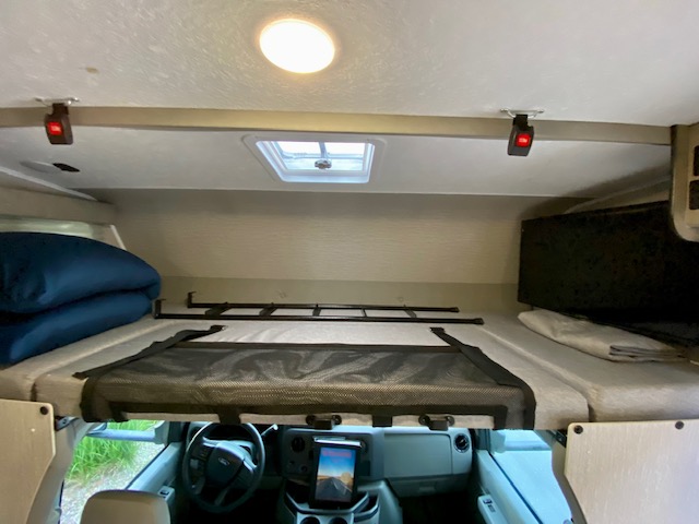 Inside an RV rental: a neat cab-over bunk sleeping area with safety net, skylight, and pillows.. Forest River Coachmen Cross Trail XL 2022