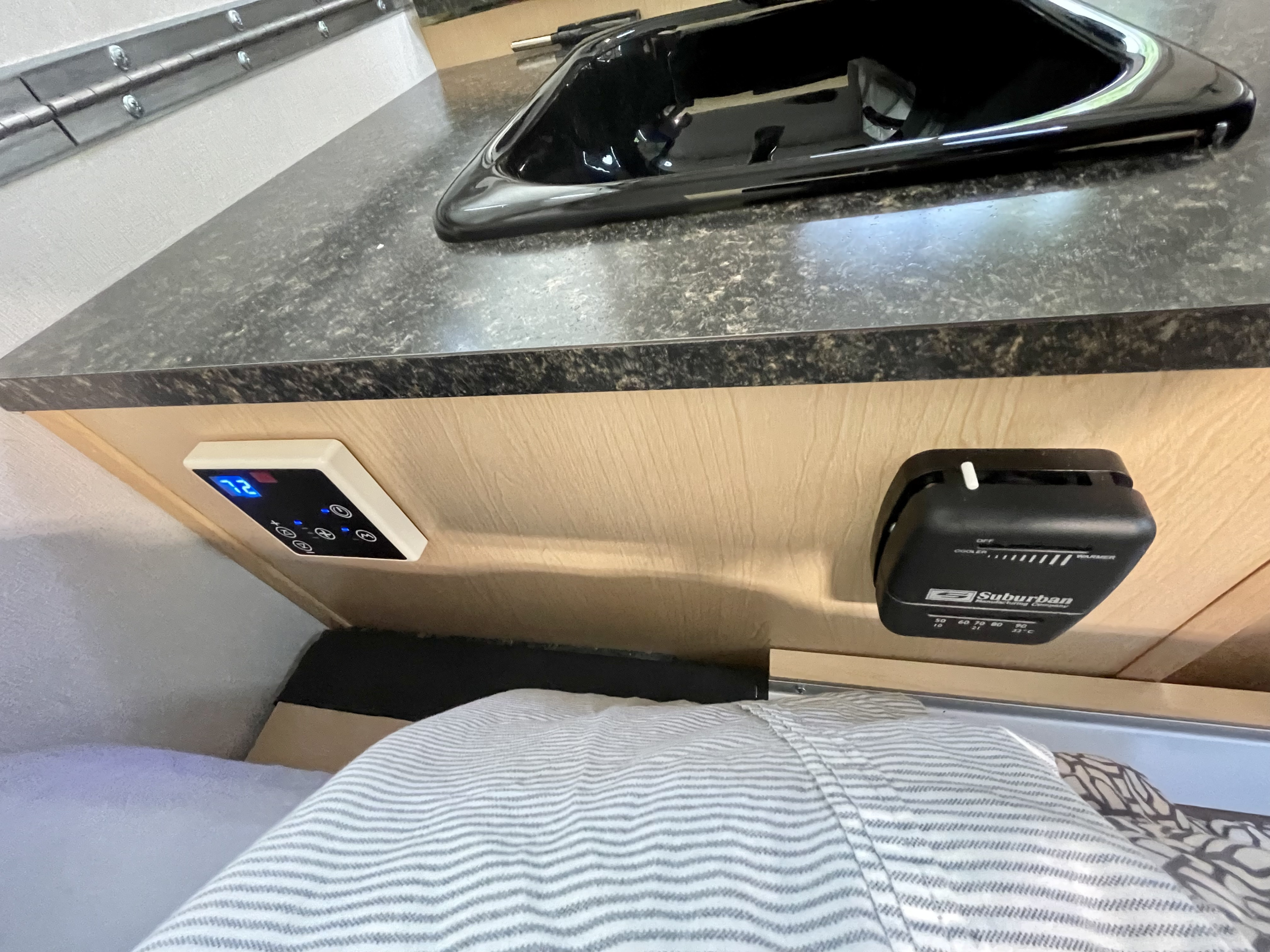 RV rental camper interior: kitchen counter with a sink, digital control panel, and a Suburban thermostat for temperature.. A Liner A Liner Popup Trailer 2023