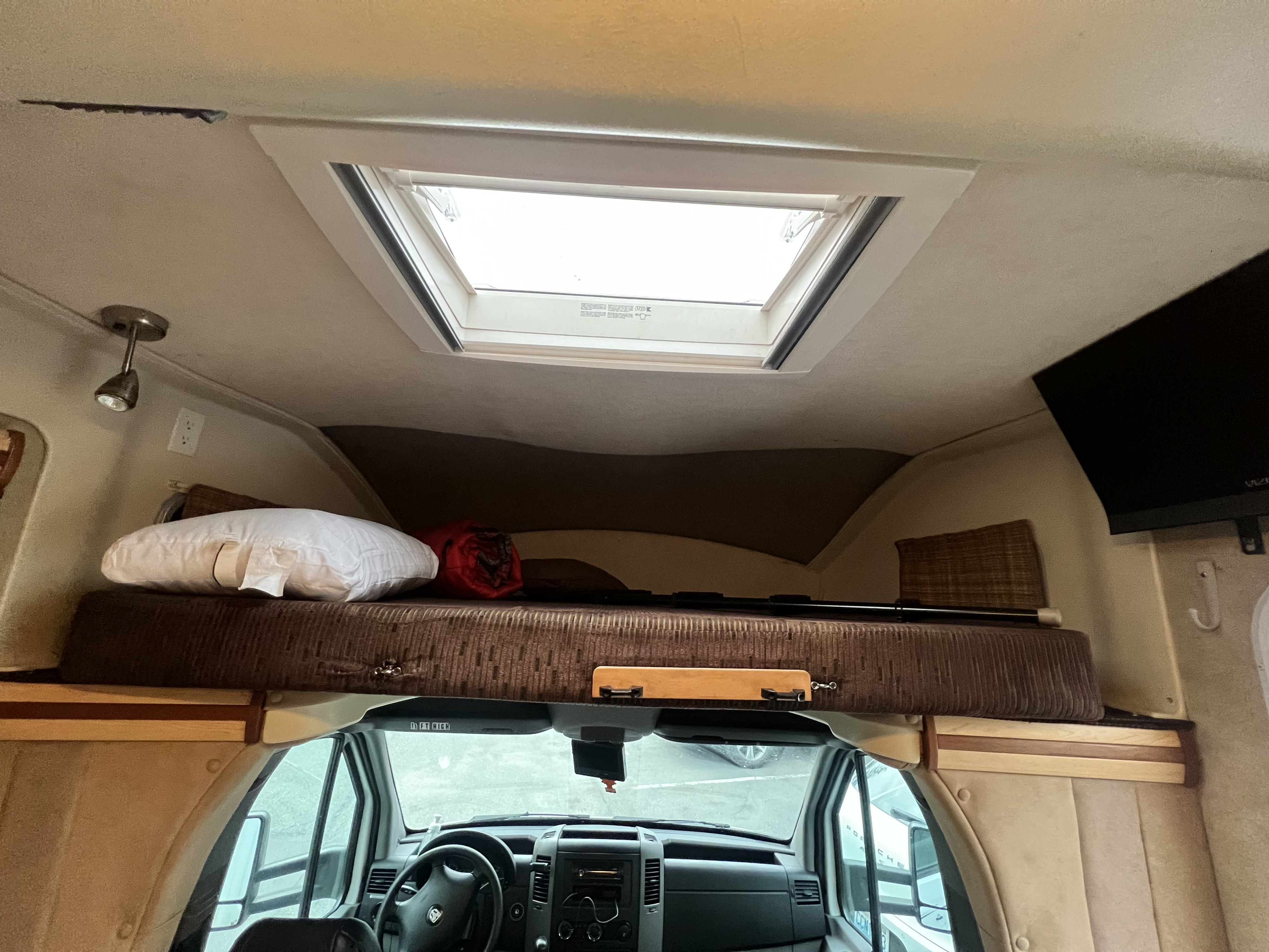 RV rental interior: cozy cabover bunk with skylight, and the front driving area with steering wheel.. Winnebago View 2008