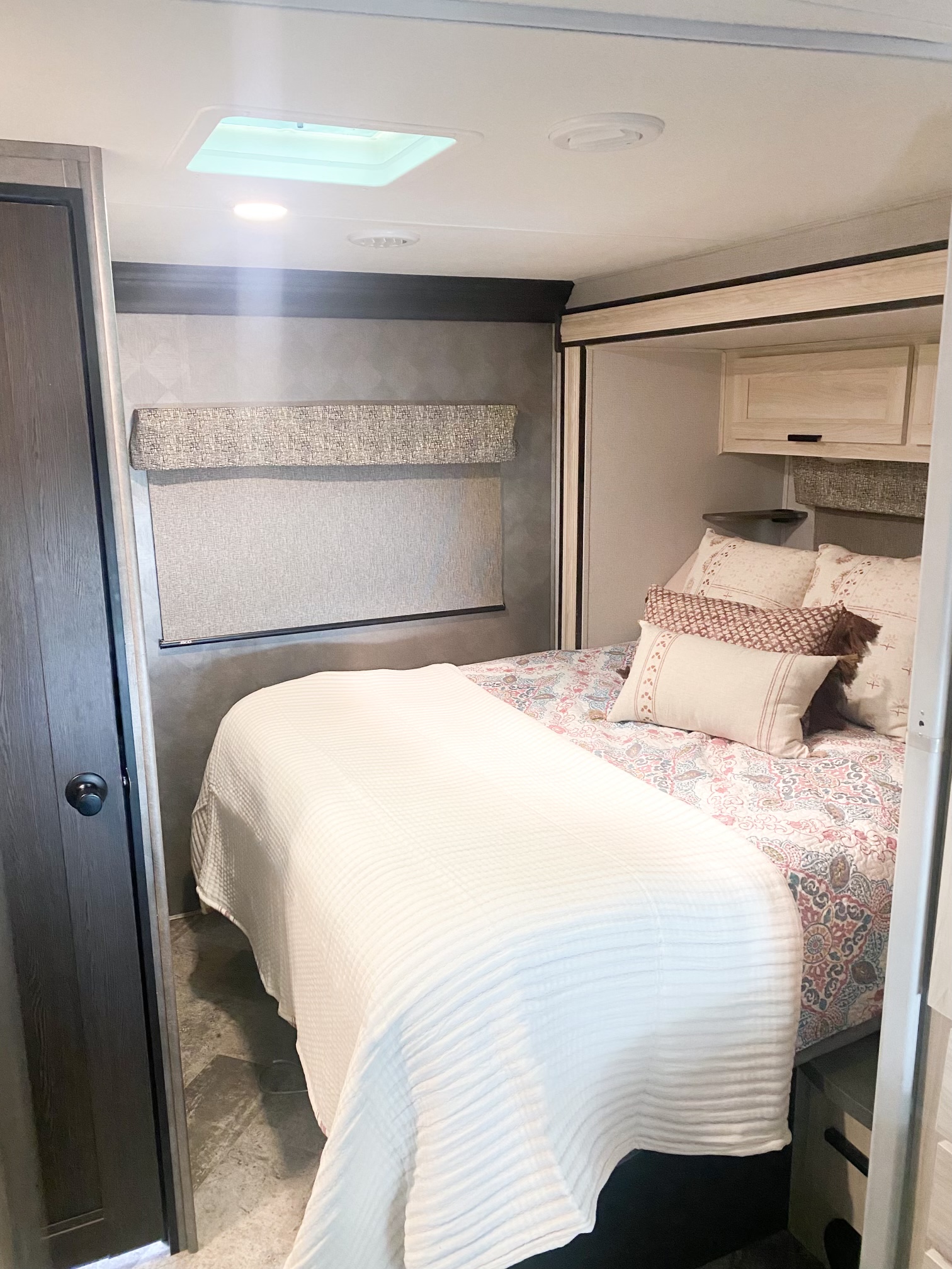 Inside an RV rental: a bright, cozy bedroom with patterned bedding, ample storage, and a large skylight.. Forester LE 2021