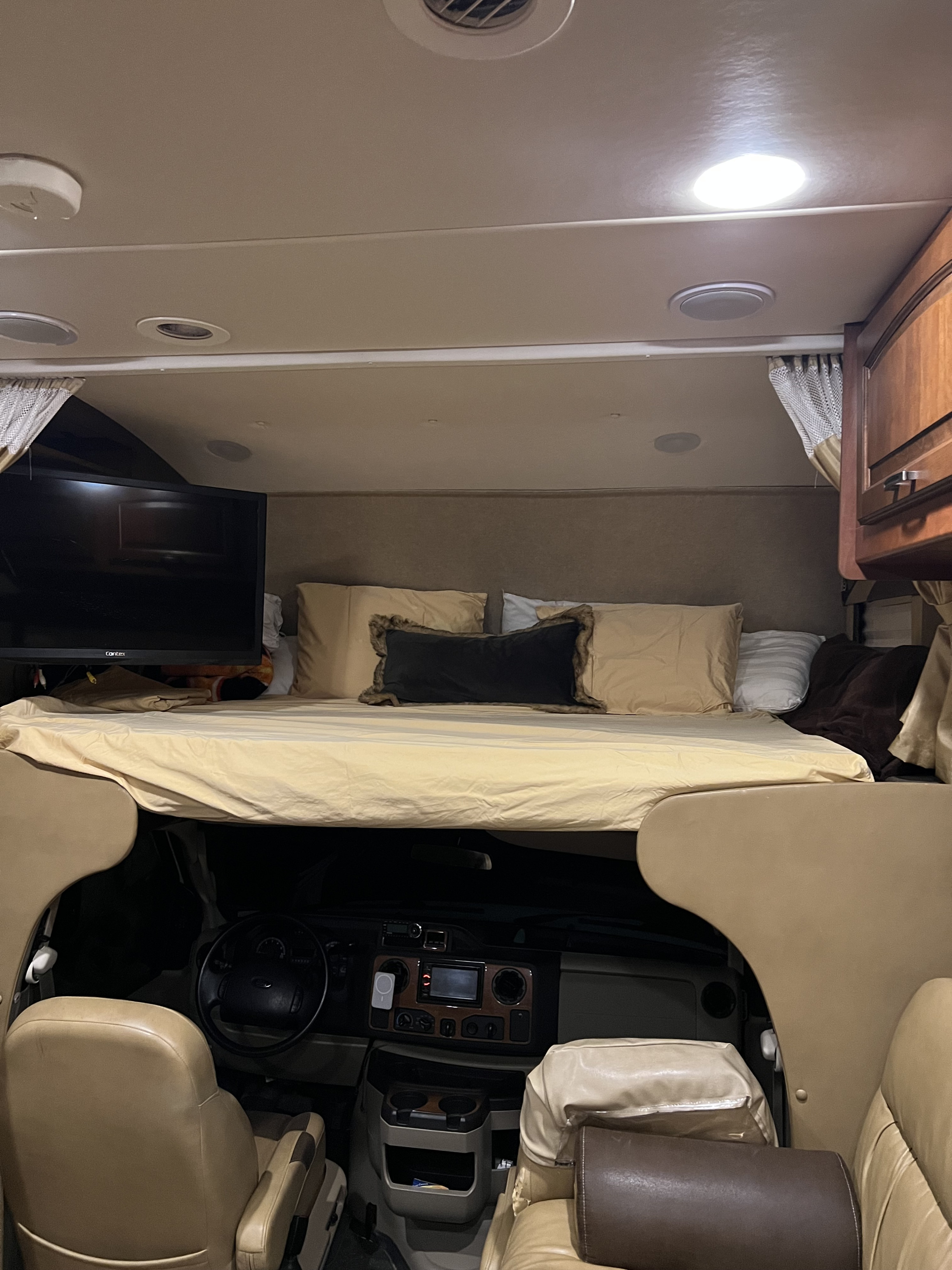 Cozy RV rental interior showing the overhead bed, TV, and cab area below. Perfect for your next road trip adventure.. Jayco Greyhawk 2015