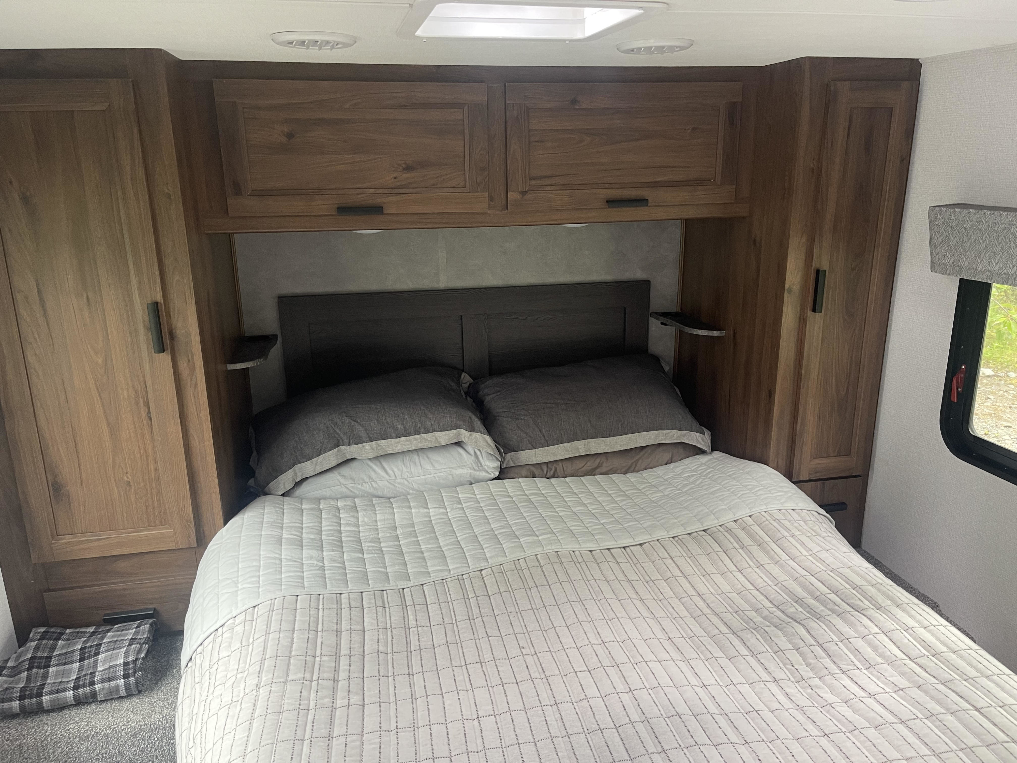 Cozy RV rental bedroom with wooden cabinets, bed, and skylight. Perfect for compact living.. Forester LE 2022