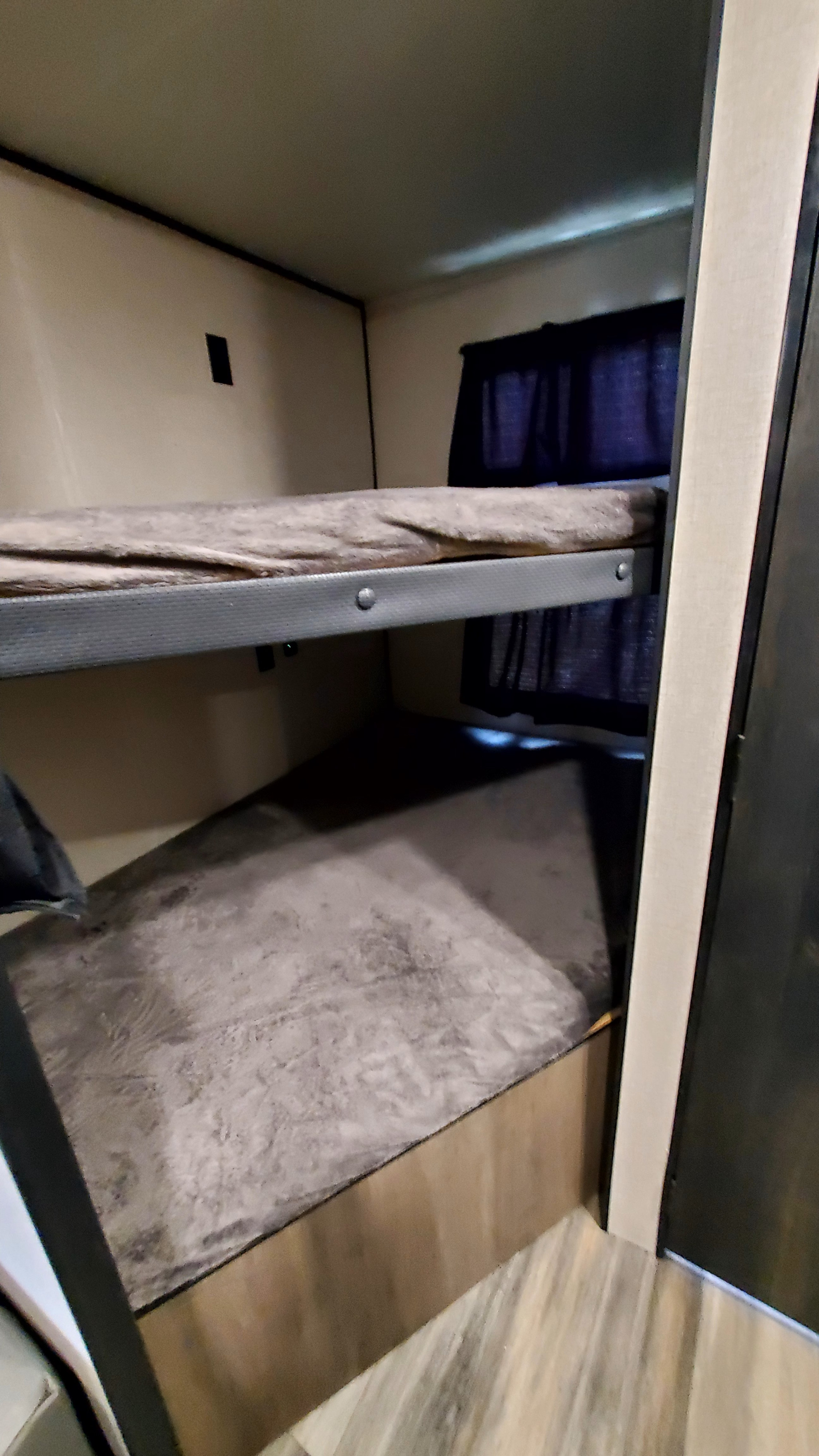Inside an RV rental: cozy bunk beds with mattresses, privacy curtains, and laminate flooring for compact sleeping.. Starcraft Autumn Ridge 2022