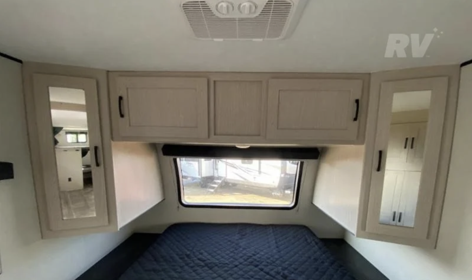 Cozy RV rental bedroom with a dark quilted bed, window, mirrored cabinets, and ceiling AC. Ideal for your next camper adventure.. Coachmen Other 2022