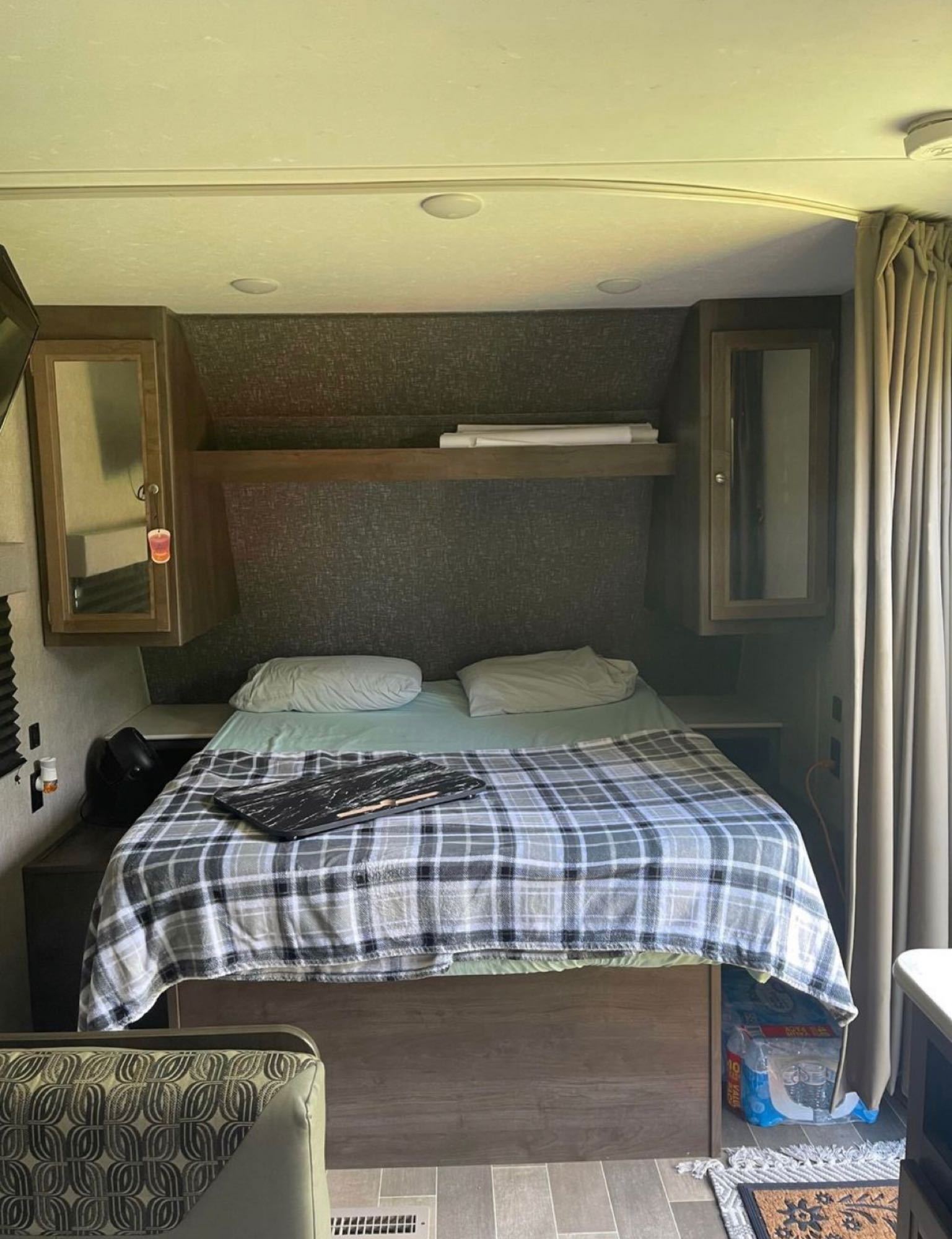 Cozy RV rental bedroom featuring a plaid-blanketed bed, overhead storage, and compact layout for travelers.. Dutchmen Coleman Lantern LT 2020