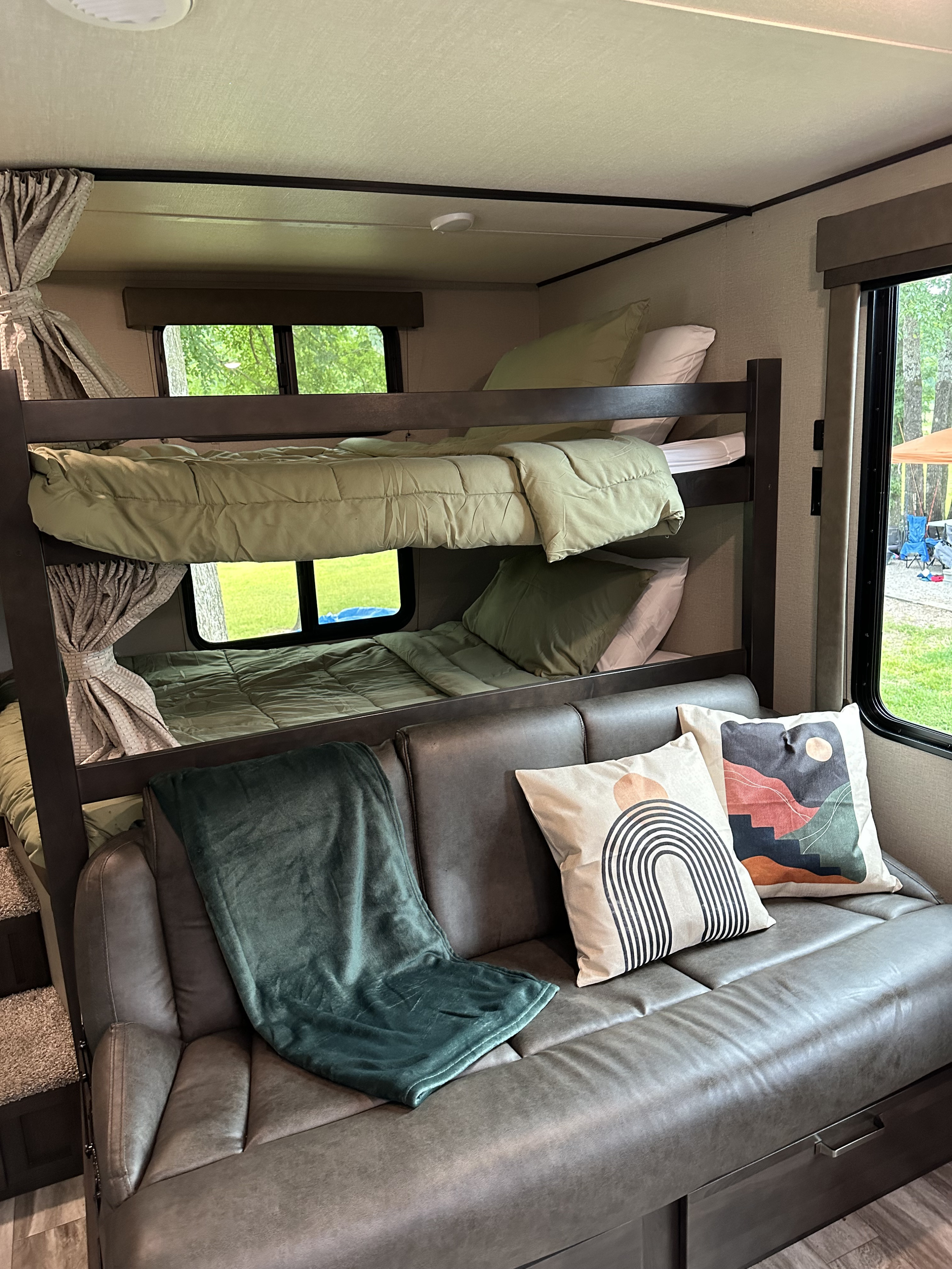 RV rental bunkhouse interior: features cozy bunk beds with green bedding and a comfortable grey sofa with decorative pillows.. Grand Design Transcend Xplor 2022