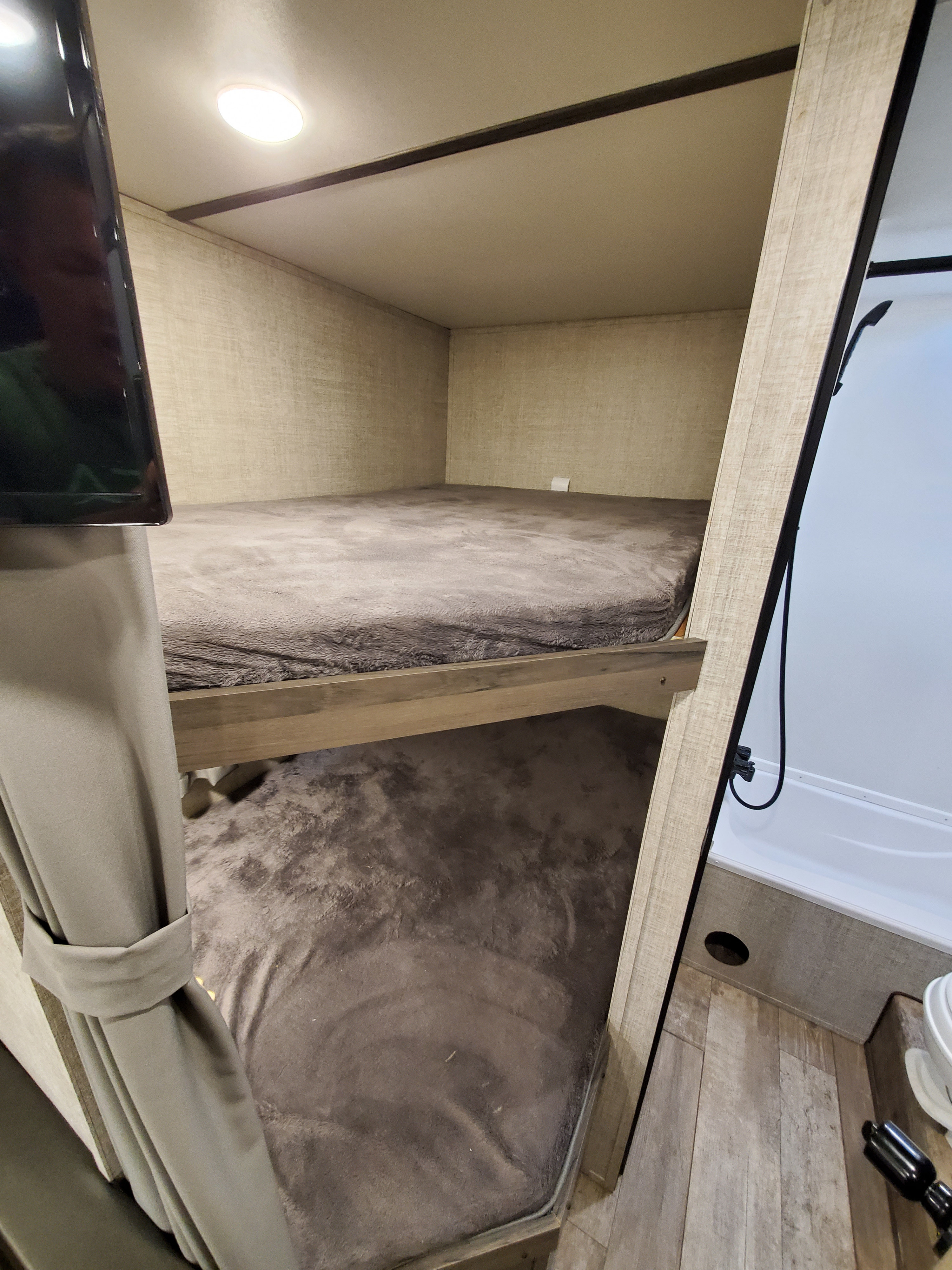Inside an RV rental: two cozy bunk beds with plush covers, next to a compact shower. Ideal for adventurous family trips.. Gulf Stream kingsport 2021