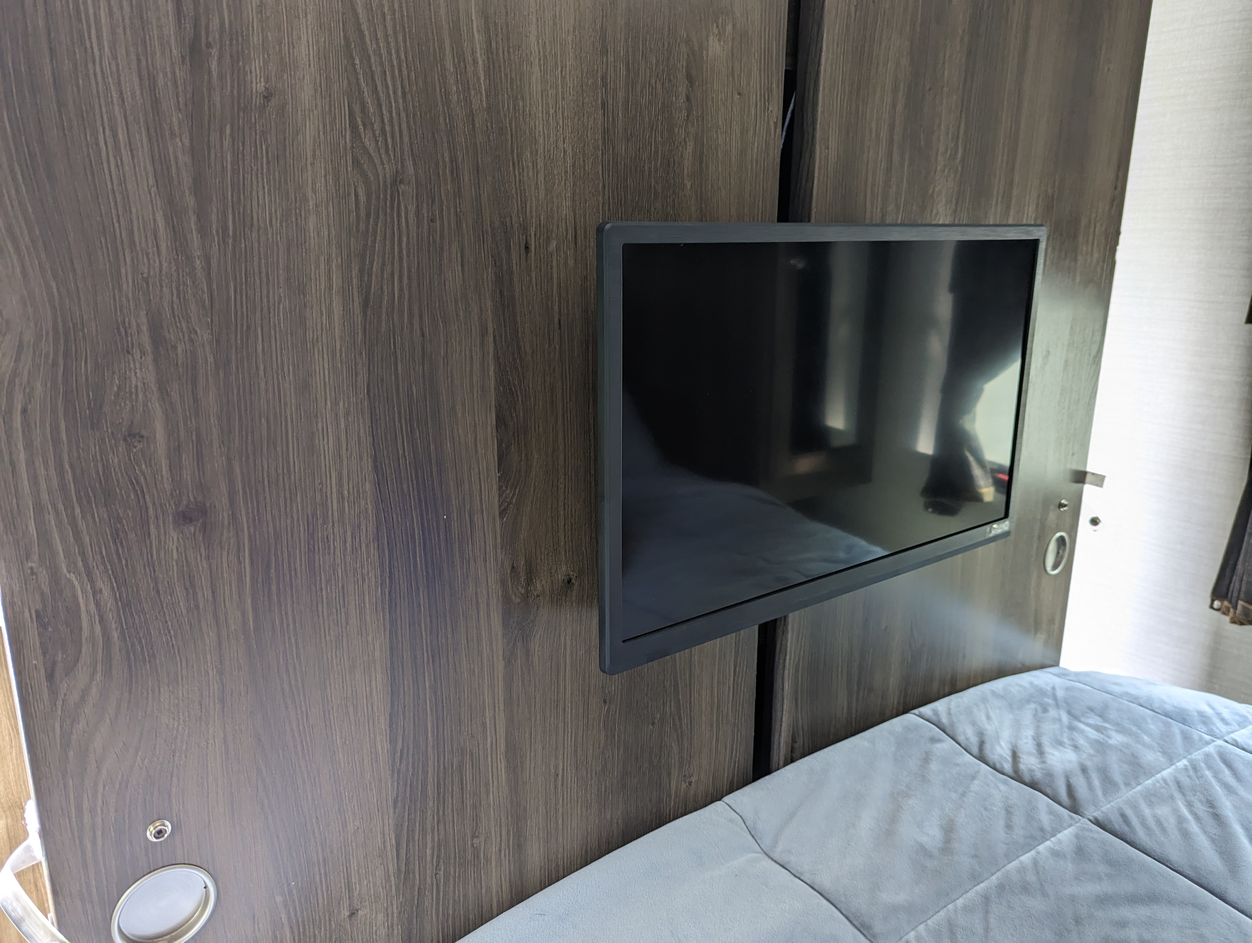 Compact TV in an RV rental bedroom, mounted on sleek wood paneling, offering entertainment.. Keystone RV Bullet Ultra Lite 2017