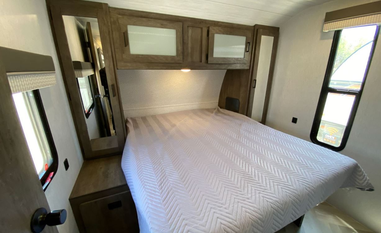 RV rental bedroom: a clean, modern space with a bed, overhead cabinets, mirror, and windows, perfect for your camper travels.. Forest River Salem 2022