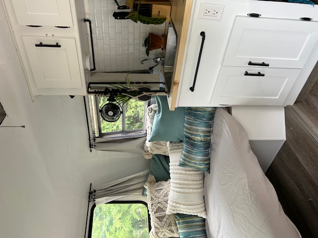 Cozy, modern RV rental interior featuring a renovated kitchen with white cabinets, wood counters, and a comfy sleeping area.. Trillium Rv Boler 13' 1975