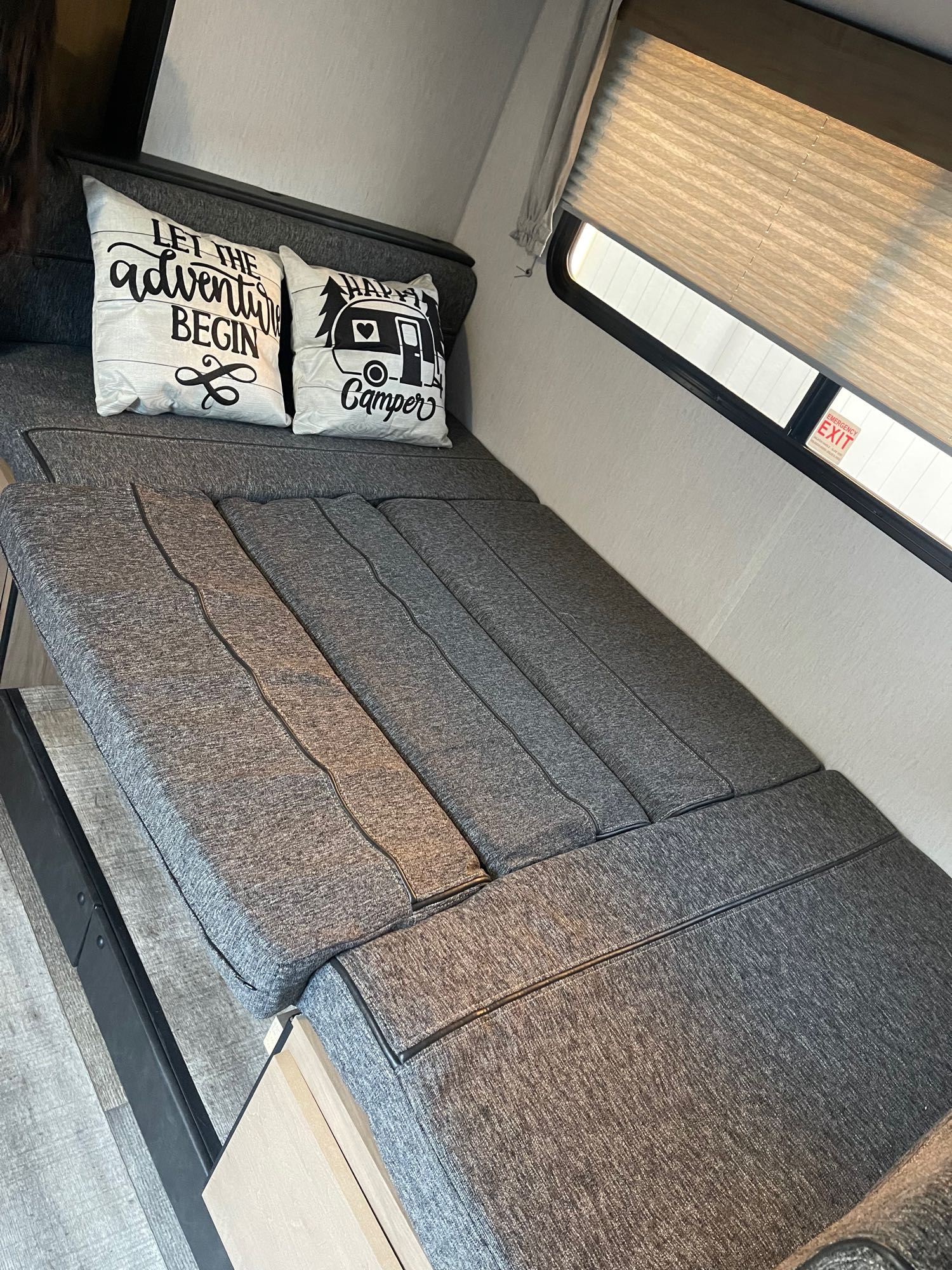 RV rental: Modern gray convertible sofa-bed inside. Features adventure pillows, window shade, and an emergency exit sign.. Forest River Cherokee Wolf Pup 2023