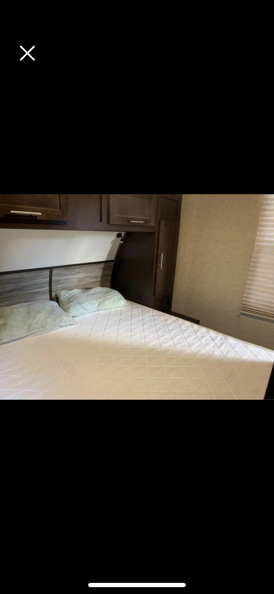 Cozy RV rental bedroom featuring a bed with a quilted pad, wood-look headboard, overhead cabinets, and window blinds.. Forest River Cherokee Grey Wolf 2018