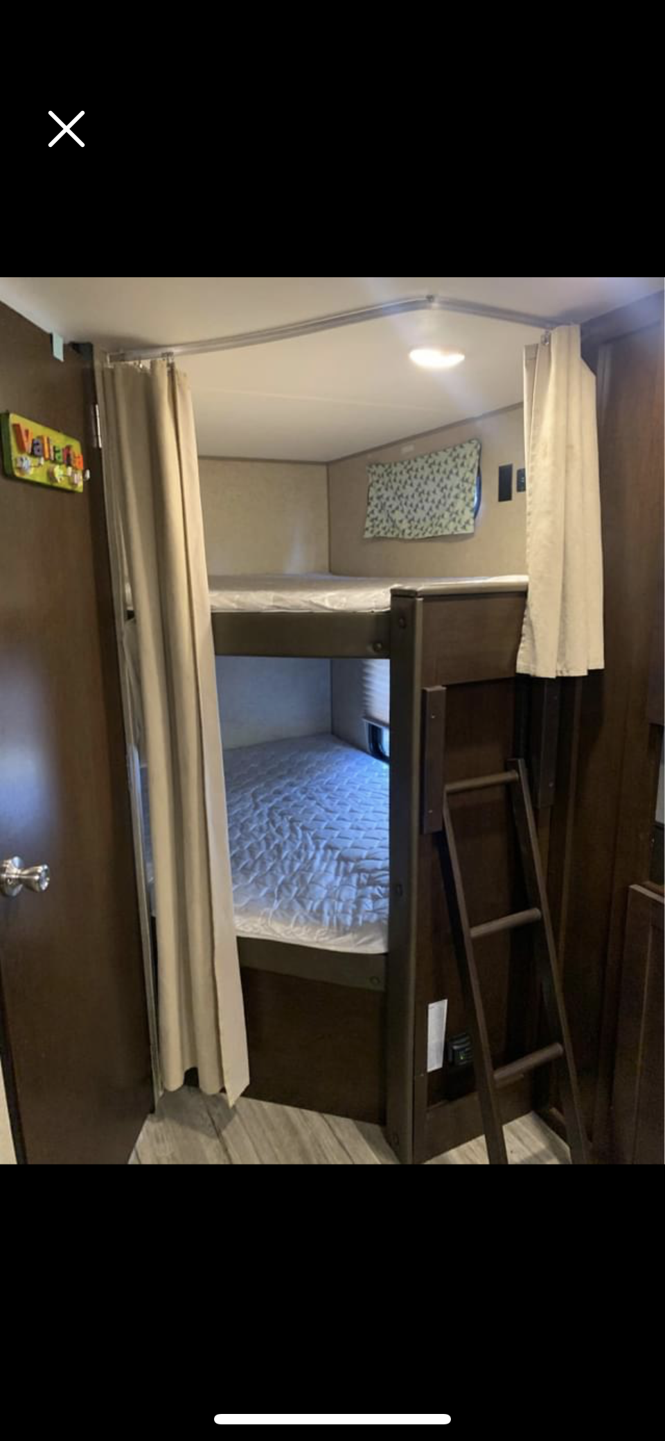 Inside an RV rental, showing a bunkhouse setup with two beds, privacy curtains, and a ladder for convenient access.. Forest River Cherokee Grey Wolf 2018