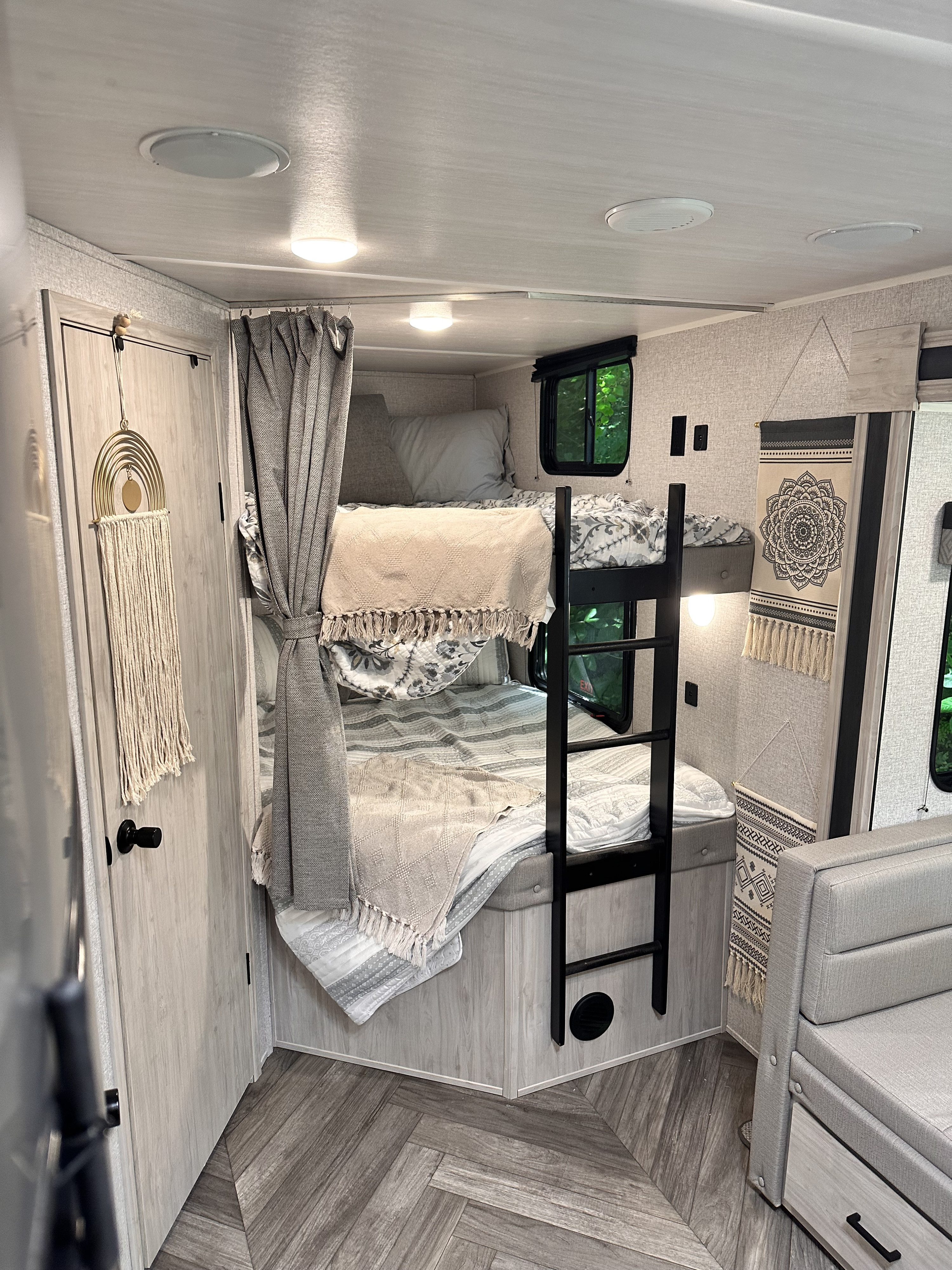 Cozy RV rental interior with light wood tones, featuring comfortable bunk beds and modern decor, ideal for family adventures.. East to West Della Terra 2022