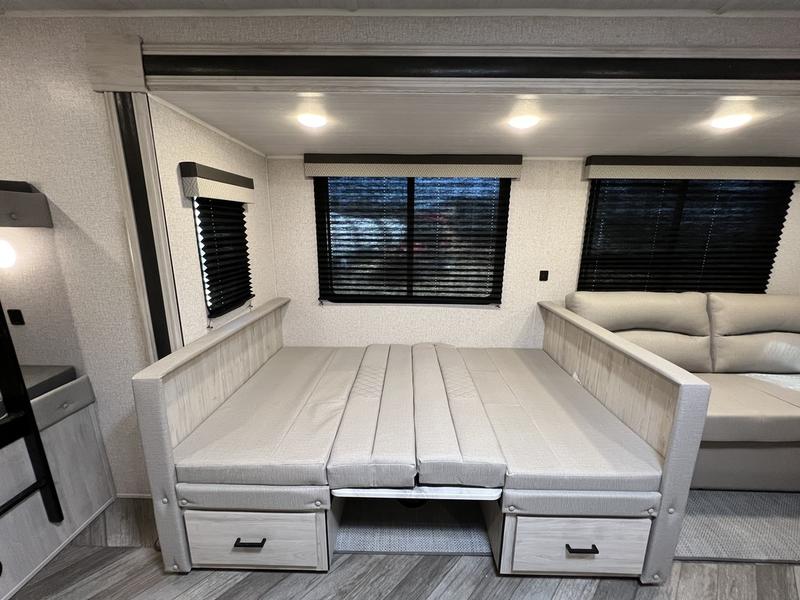 RV rental: Bright RV interior featuring a light-colored convertible sofa bed with storage drawers below. Two windows are visible.. East to West Della Terra 2022