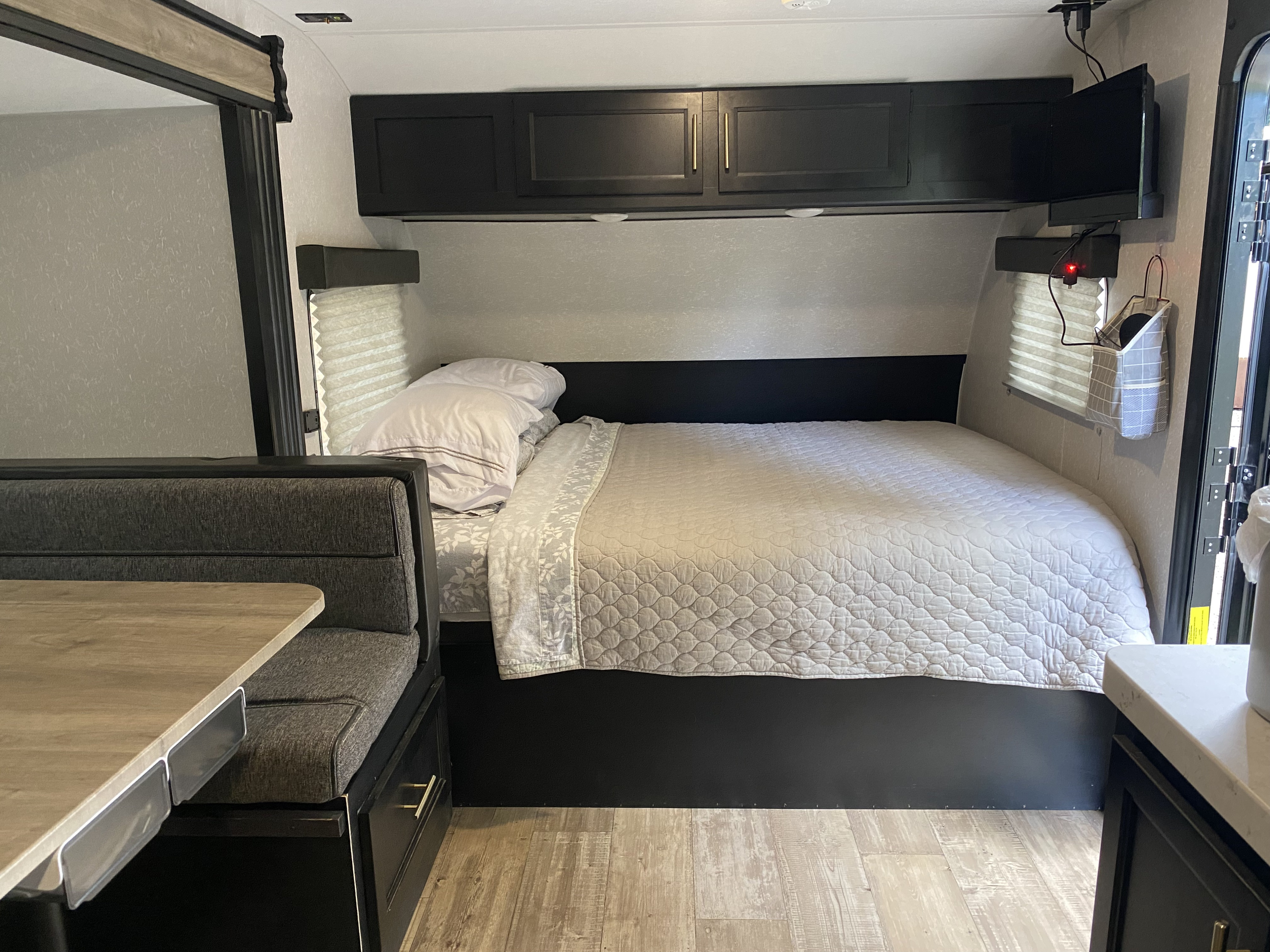 Comfortable RV rental bedroom and dinette area, showing compact living space with storage and a TV.. Forest River Cherokee Wolf Pup 2021