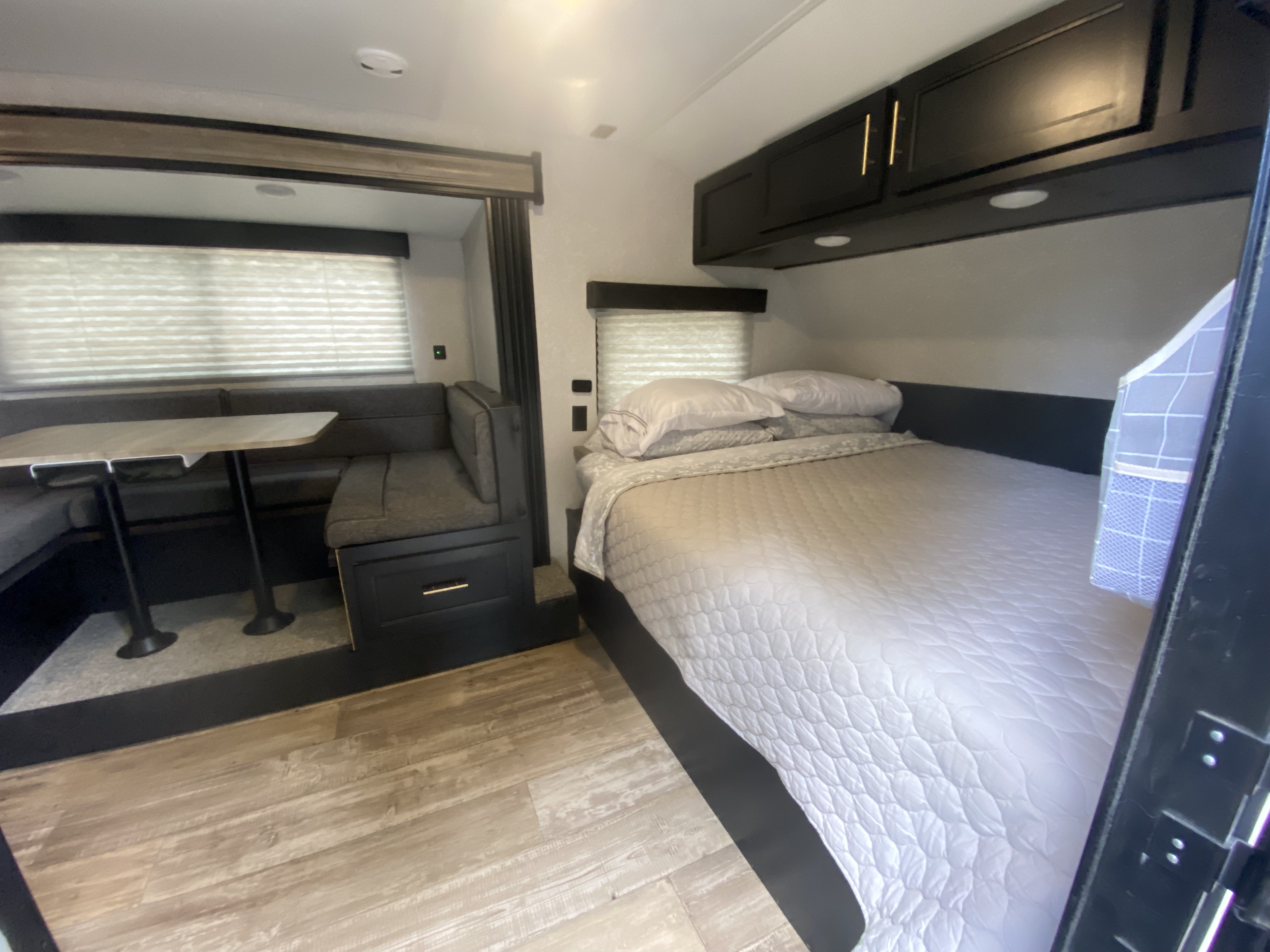 Spacious RV rental interior featuring a comfortable bed, functional dinette, and overhead cabinets for storage.. Forest River Cherokee Wolf Pup 2021