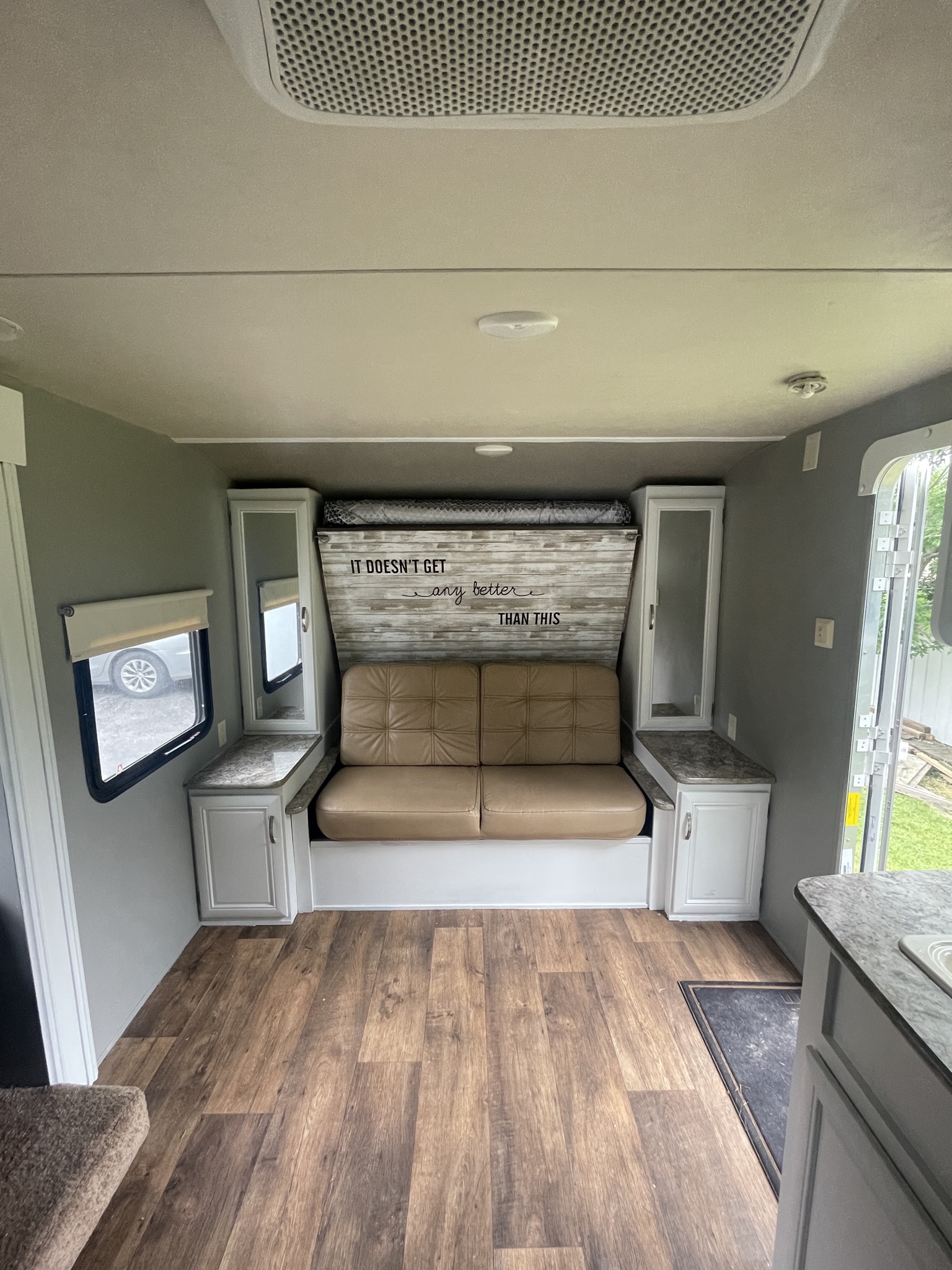 RV rental's inviting interior: convertible couch/bed, wood-look floor, white storage cabinets, and bright windows.. Forest River Wildwood X-Lite 2016