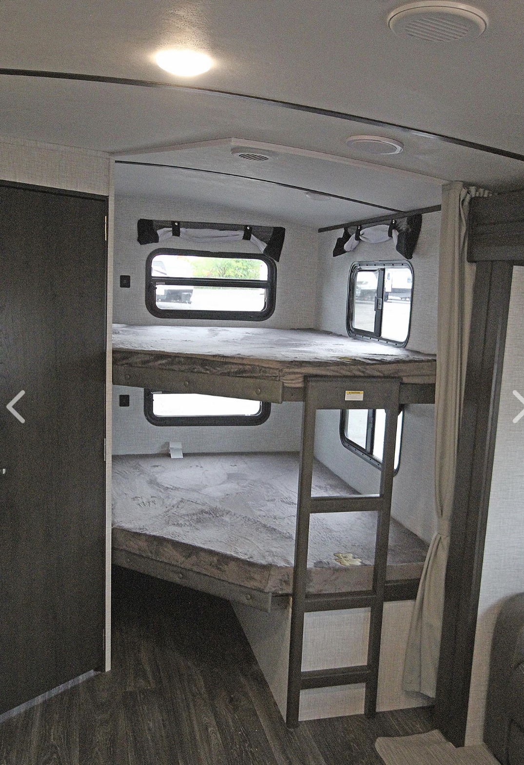 Inside an RV rental: a cozy bunkhouse area with two beds, windows, and a ladder, great for family travel.. Keystone RV Bullet Ultra Lite 2021
