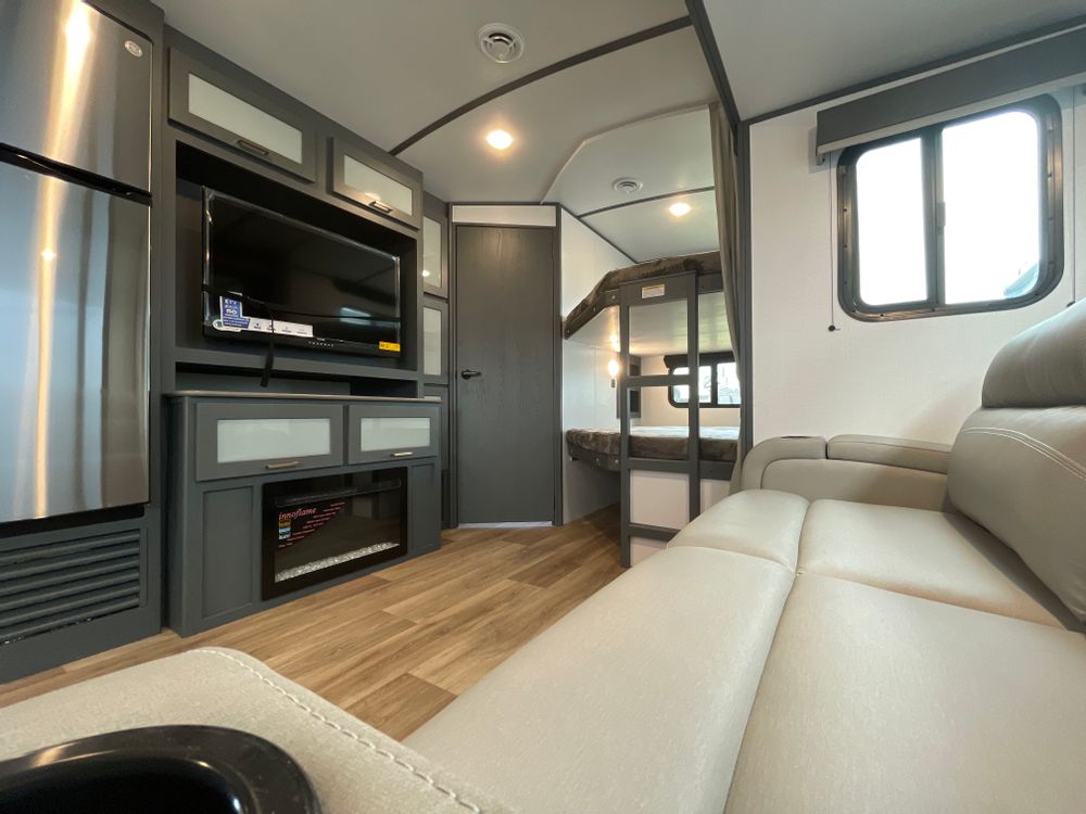 Modern RV rental interior showing living area with sofa, kitchen, entertainment center, and bunk beds. Perfect for family trips!. Keystone RV Bullet Ultra Lite 2023