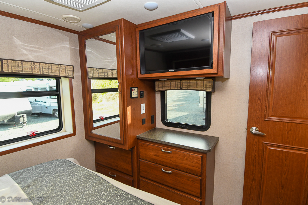 RV rental bedroom with bed, windows, built-in dresser, TV, and mirror, offering comfort on the go.. Isata 5 2018