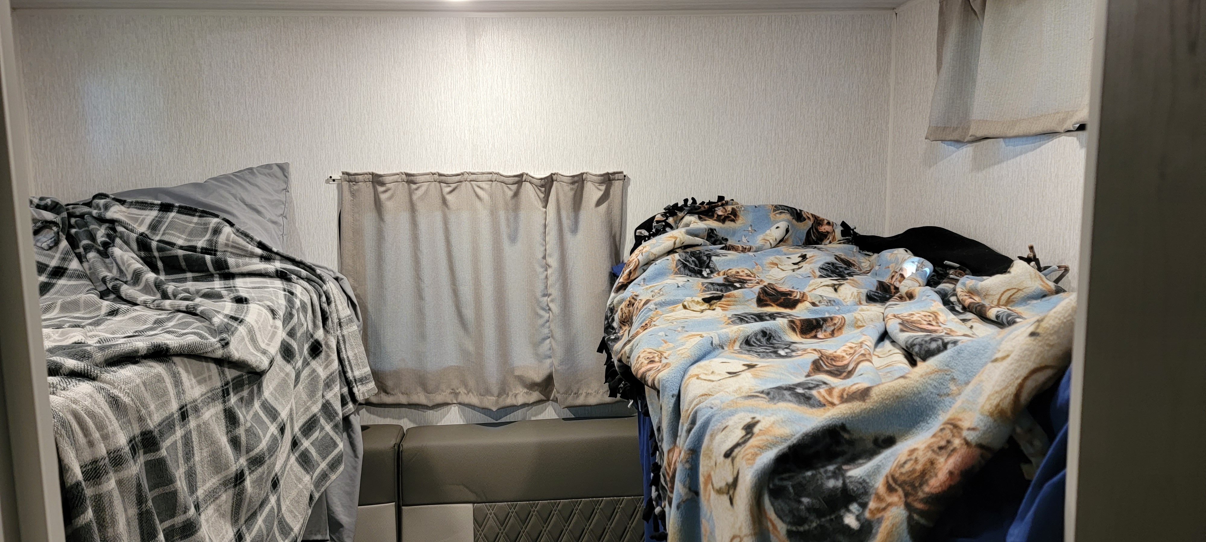 Inside an RV rental, two bunk beds with cozy blankets and a central window create a compact sleeping area for travelers.. Forest River Salem Cruise Lite 2023