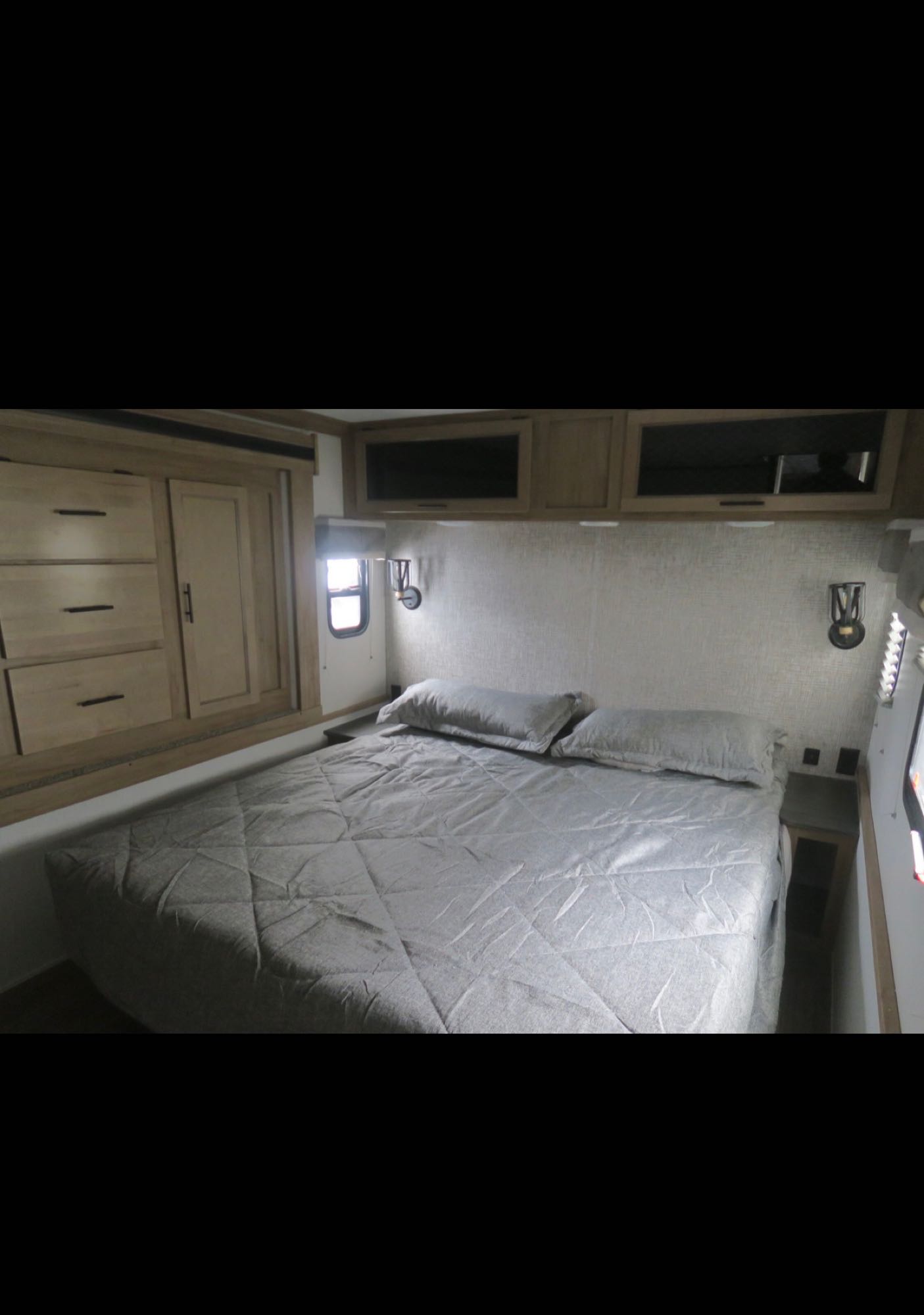 Cozy RV rental bedroom featuring a queen bed, built-in storage, and reading lights, ready for your adventure.. Forest River Sabre 37FLL 2023
