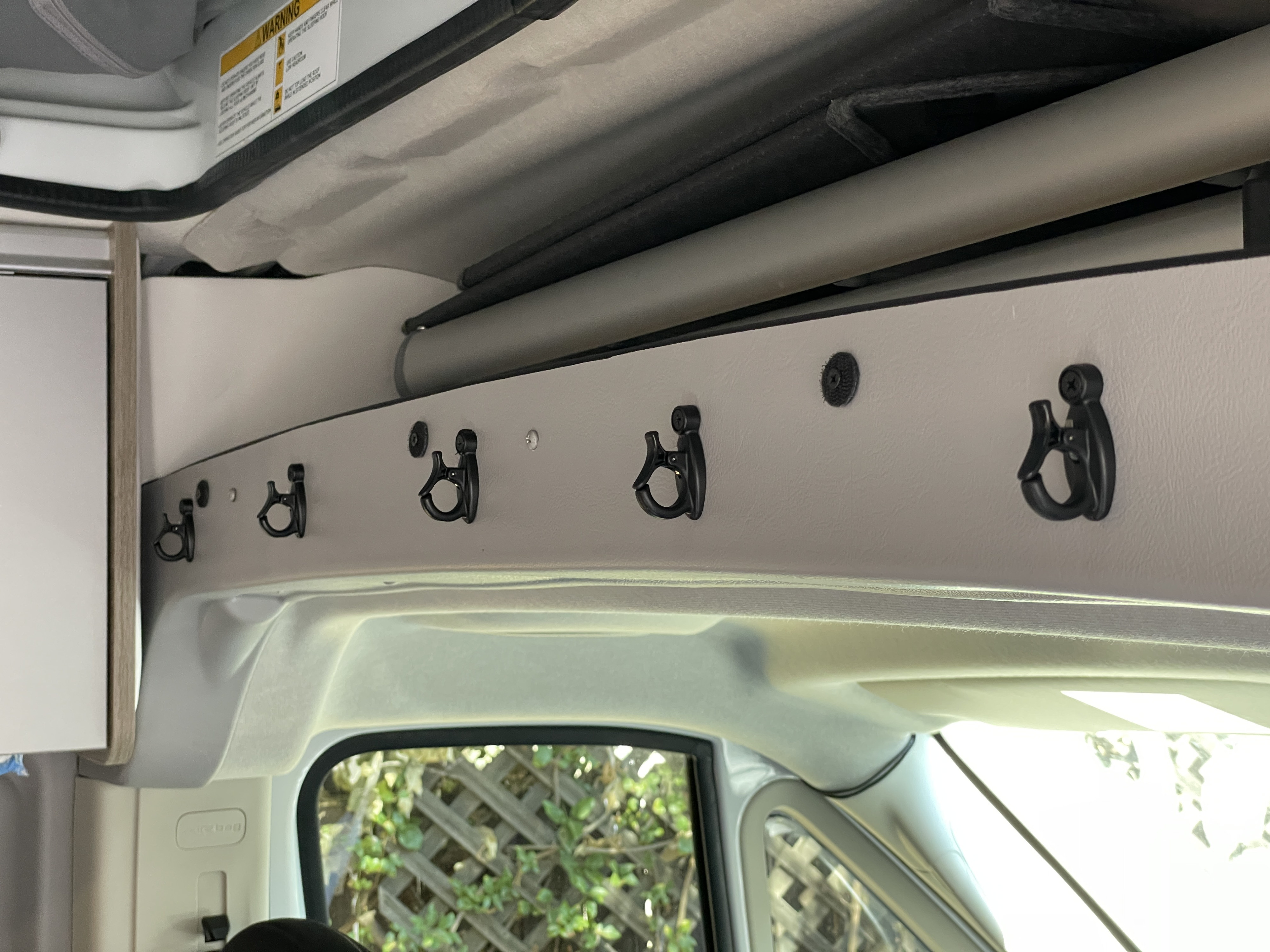 RV rental interior: Black ceiling-mounted utility hooks and overhead bars provide smart storage solutions.. Winnebago Solis 2021