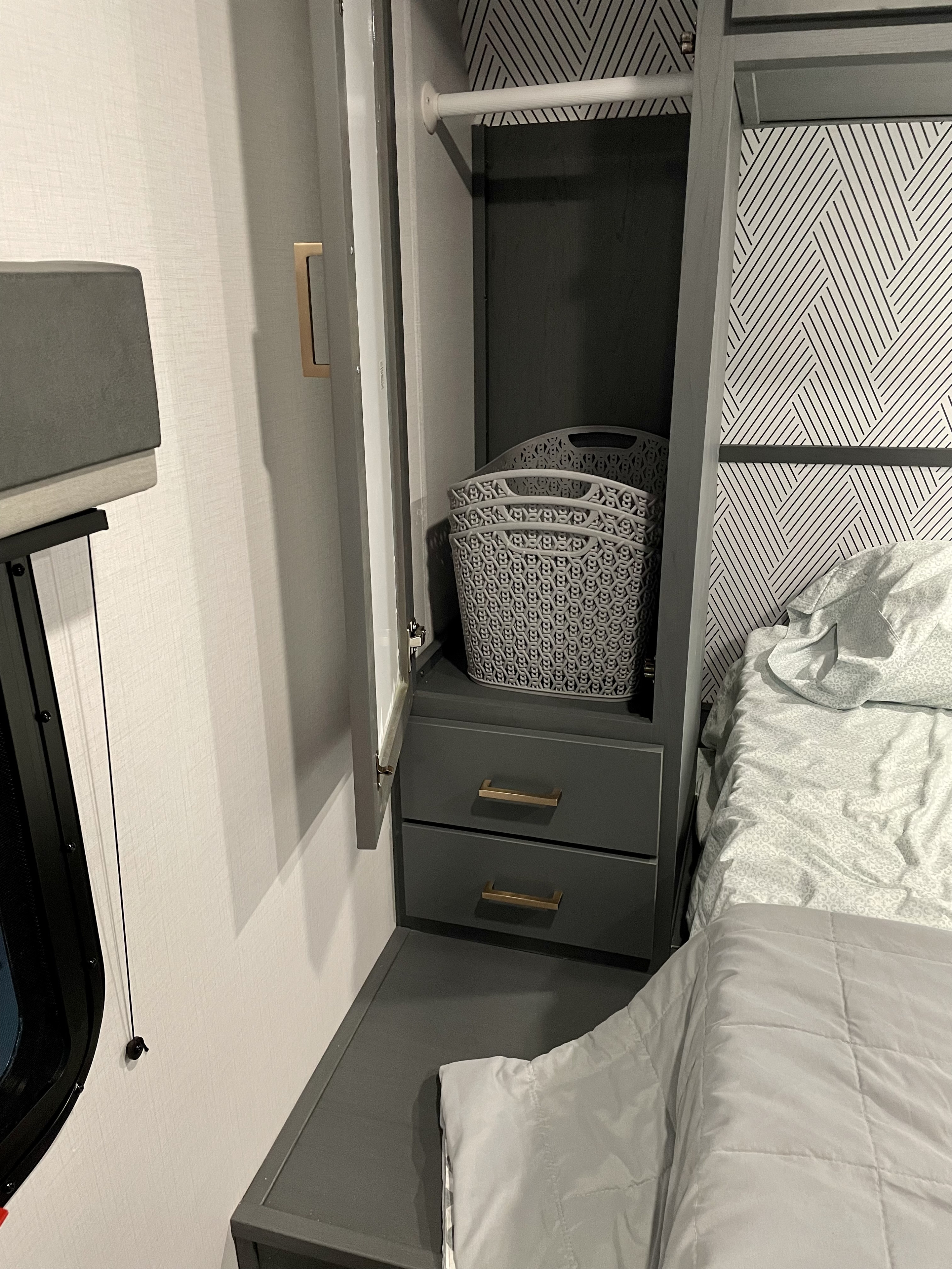 Cozy RV rental bedroom features a built-in wardrobe, drawers, and geometric wallpaper, ready for your next adventure.. Keystone RV Bullet Ultra Lite 2022