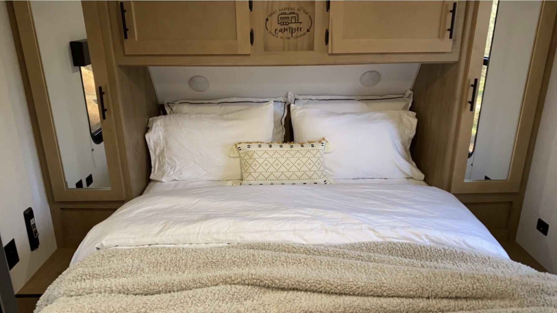 Comfortable RV rental bedroom featuring a neatly made bed, white linens, and overhead storage.. Forest River Cherokee, Grey Wolf 23MK 2023
