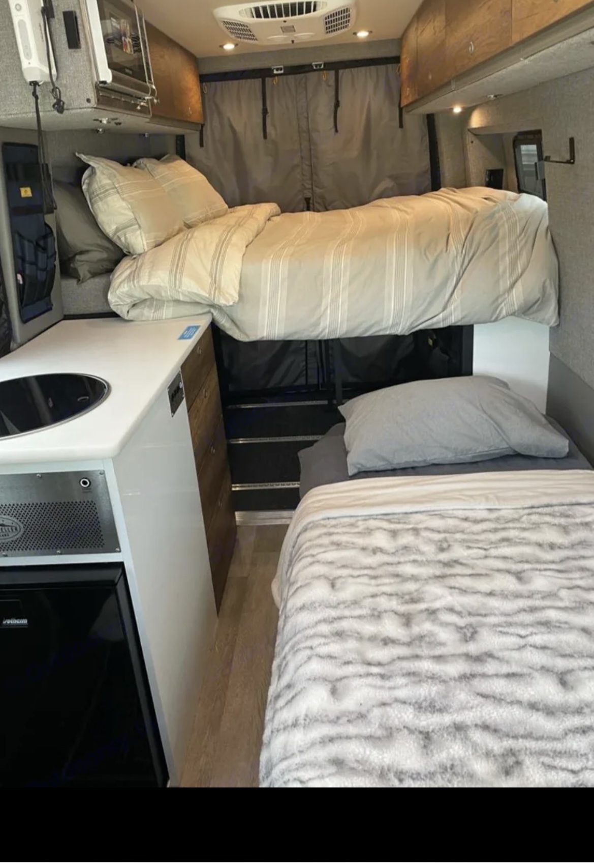 This RV rental features a multi-level sleeping area (bunk beds) and a compact kitchenette with a sink & fridge, ideal for travel.. Mercedes-Benz sprinter 2023