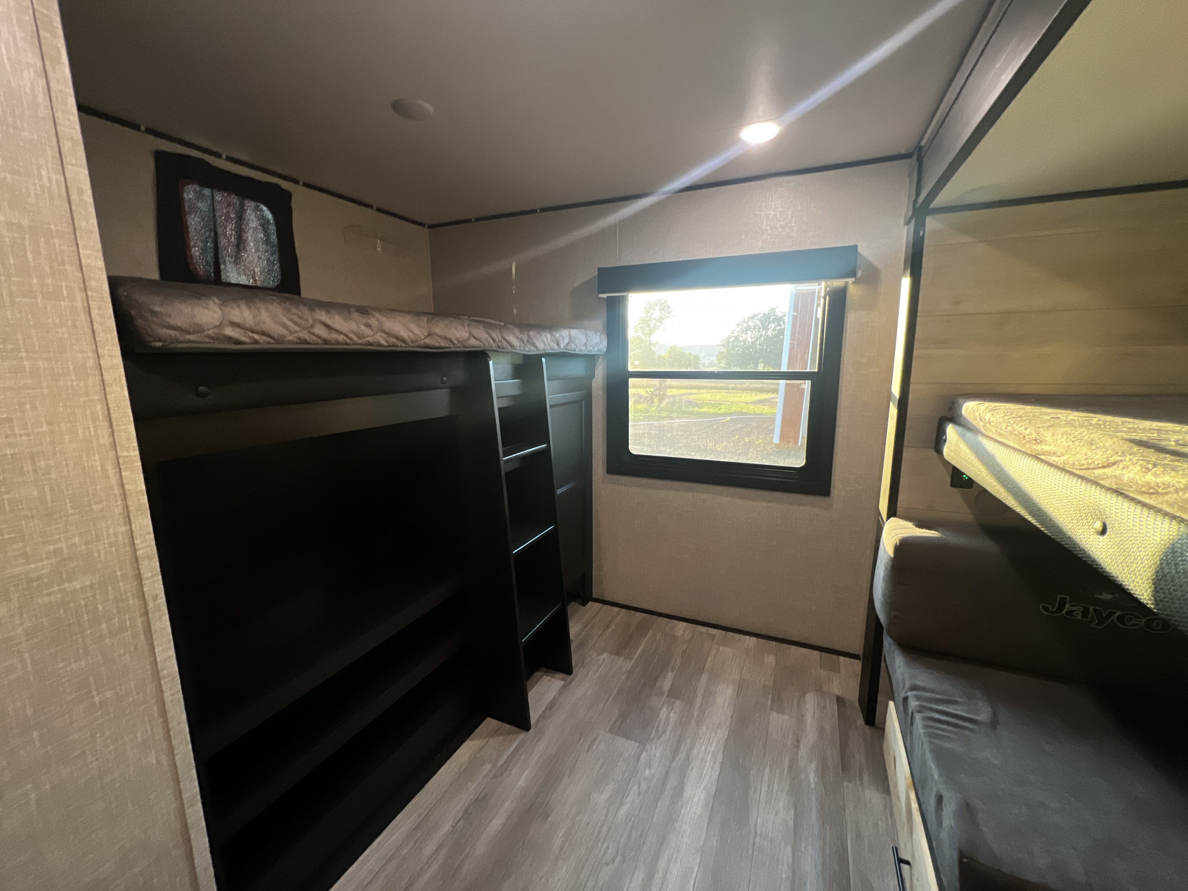 Cozy RV rental bunkhouse interior with multiple beds, a window view, and light wood-look flooring.. Jayco Jay Flight 2023