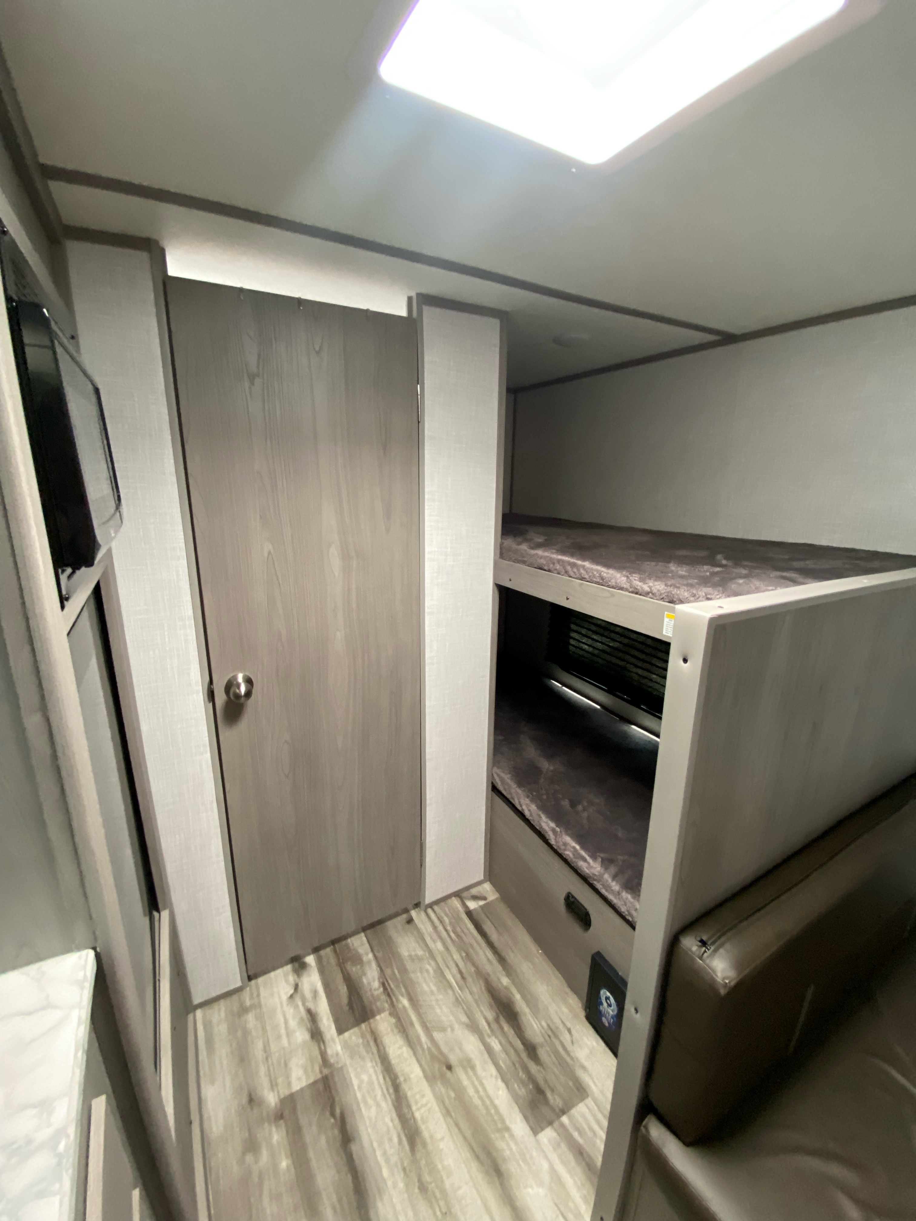 Spacious RV rental interior with bunk beds, microwave, and wood flooring. Perfect for your next adventure!. Dutchmen Coleman Lantern LT 2023