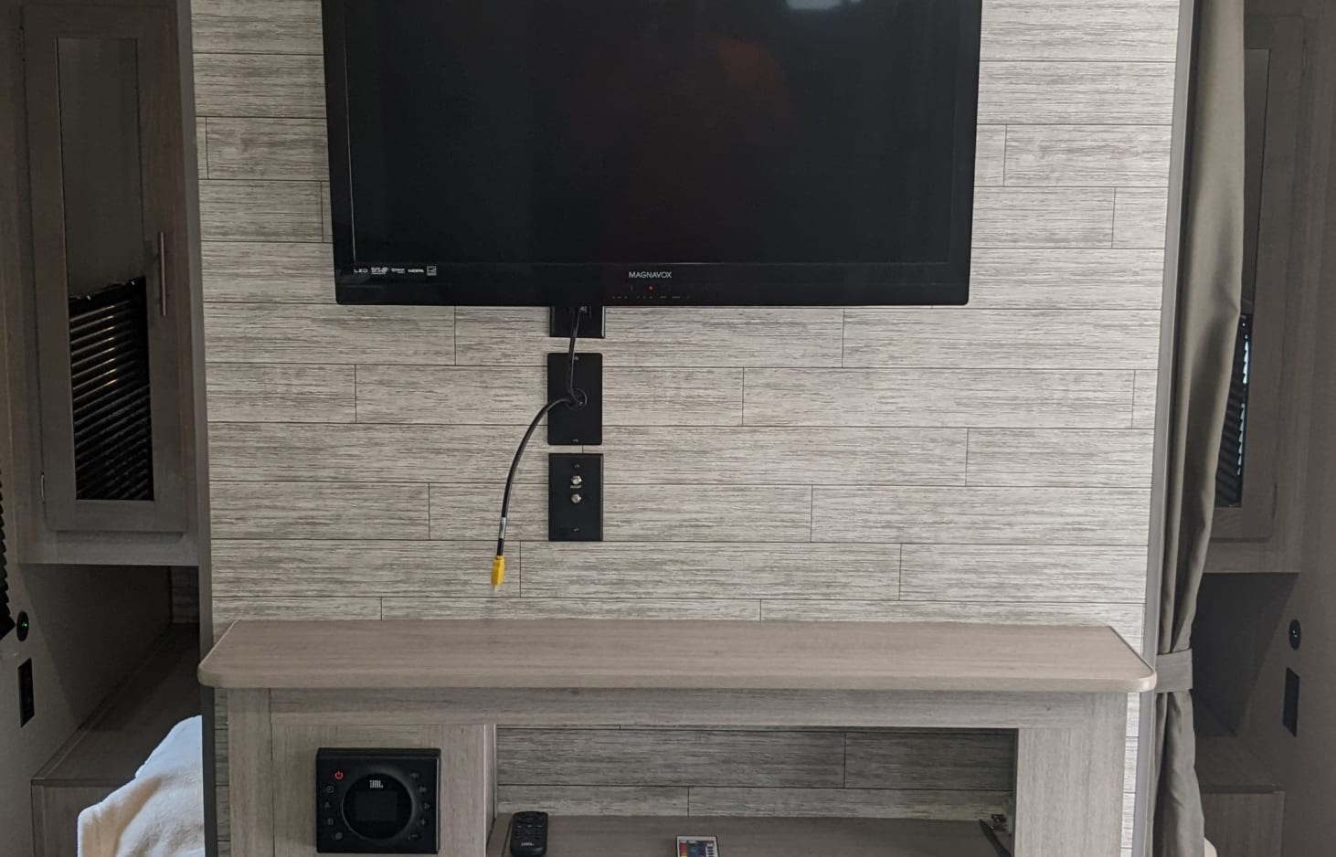 Modern RV rental living space featuring a mounted TV, JBL audio system, and light wood-textured walls.. Coachmen Other 2023