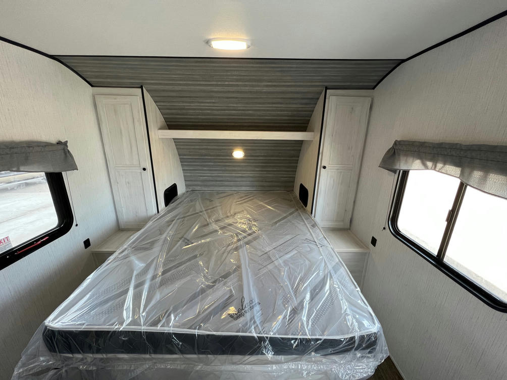 Clean RV rental bedroom with new mattress in plastic, built-in cabinets, and windows. Perfect for your next adventure.. Heartland RVs Trail Runner 2022
