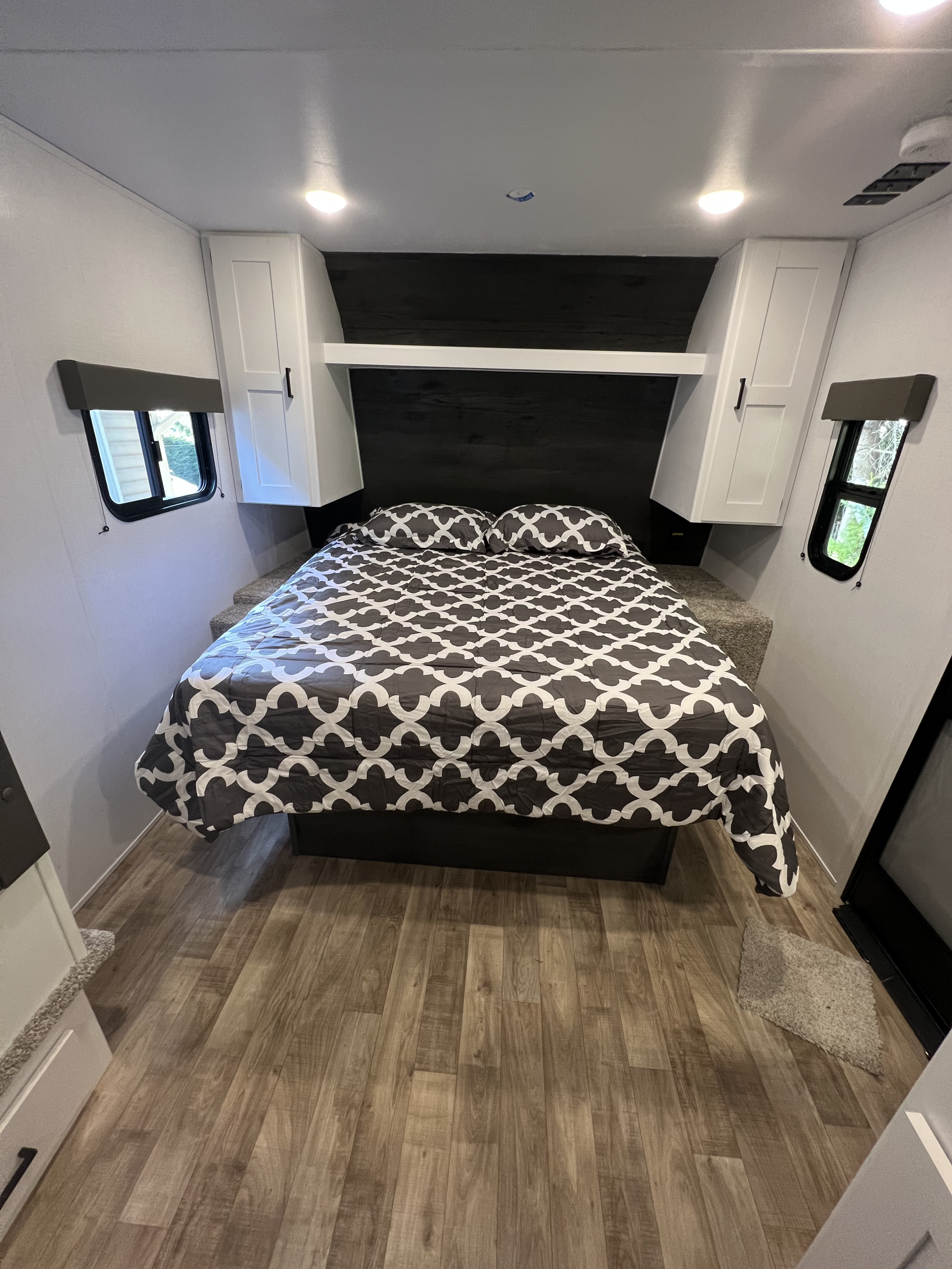 Step inside this cozy rv rental bedroom, featuring a large bed, overhead storage, side windows, and modern finishes.. Keystone RV Hideout 2022
