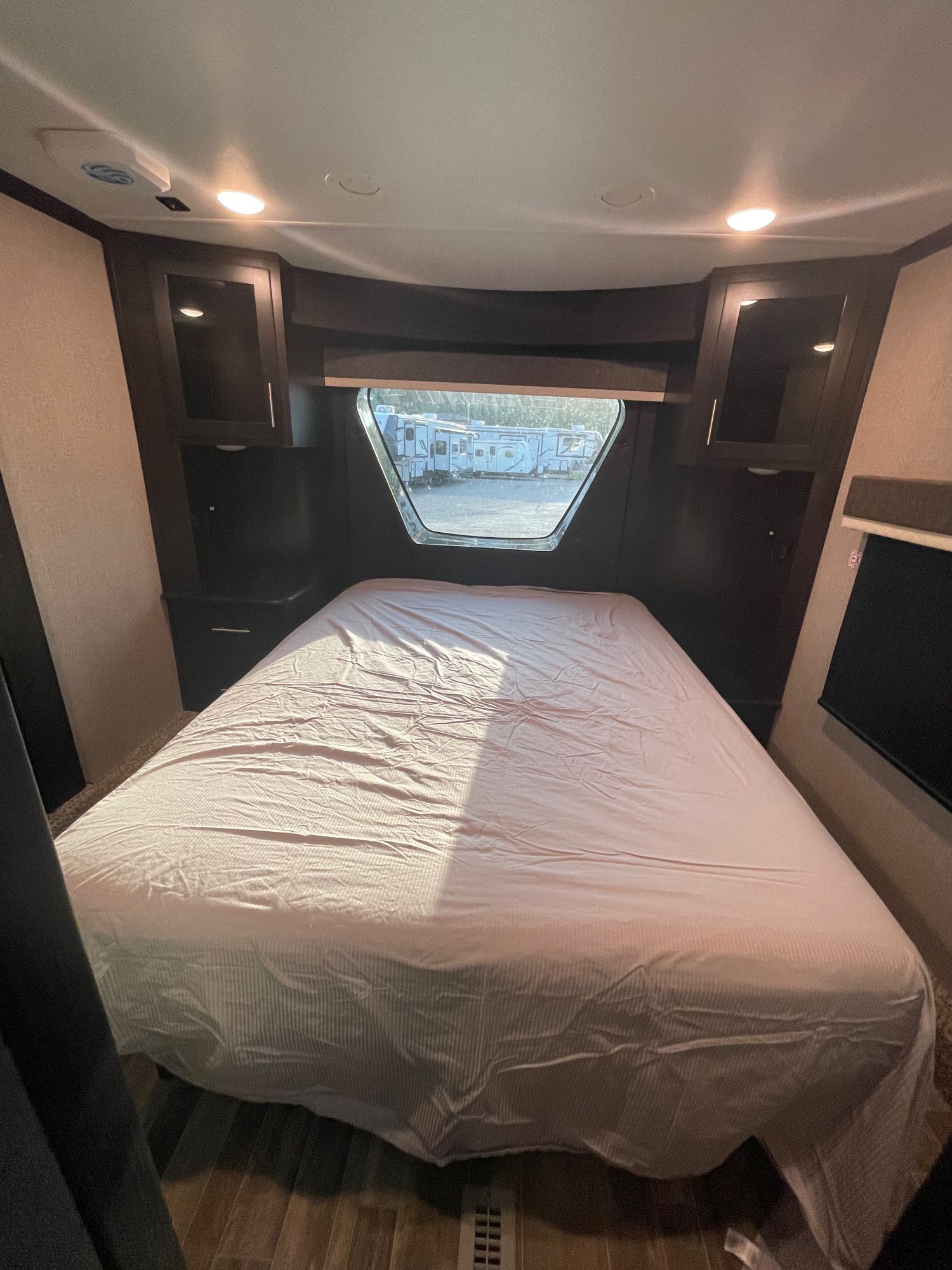 RV rental bedroom: cozy space with a bed, dark wood storage, and large window view.. Jayco seismic 4113 2021