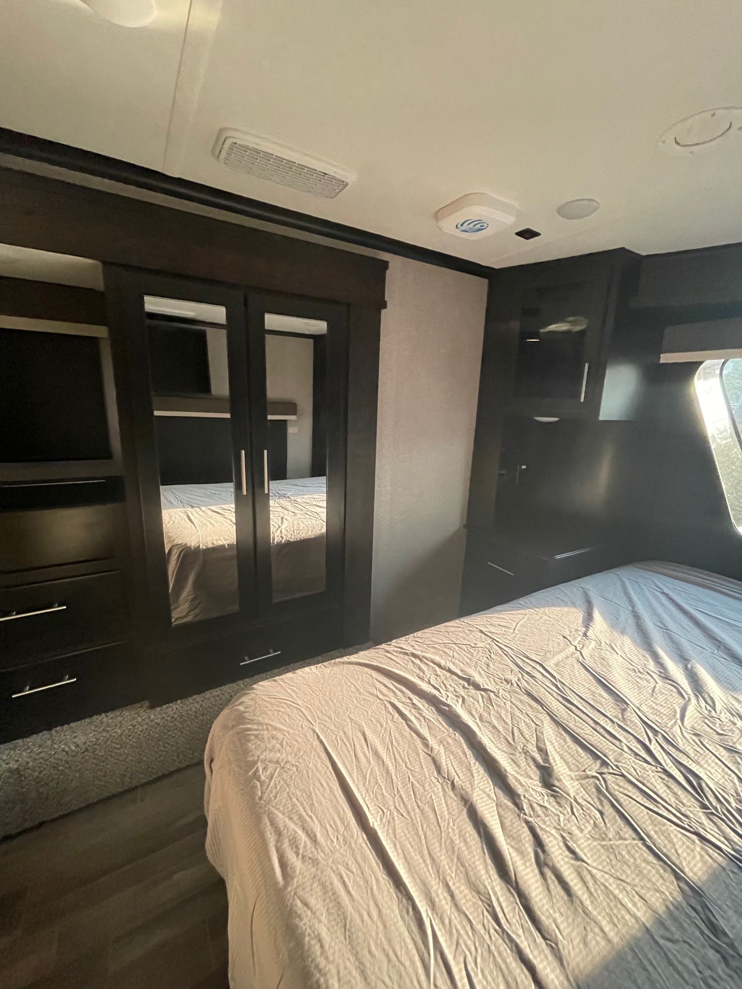 Spacious RV bedroom interior, showcasing a comfortable bed, wardrobe with mirrored doors, and built-in TV console. Perfect for your next RV rental adventure.. Jayco seismic 4113 2021