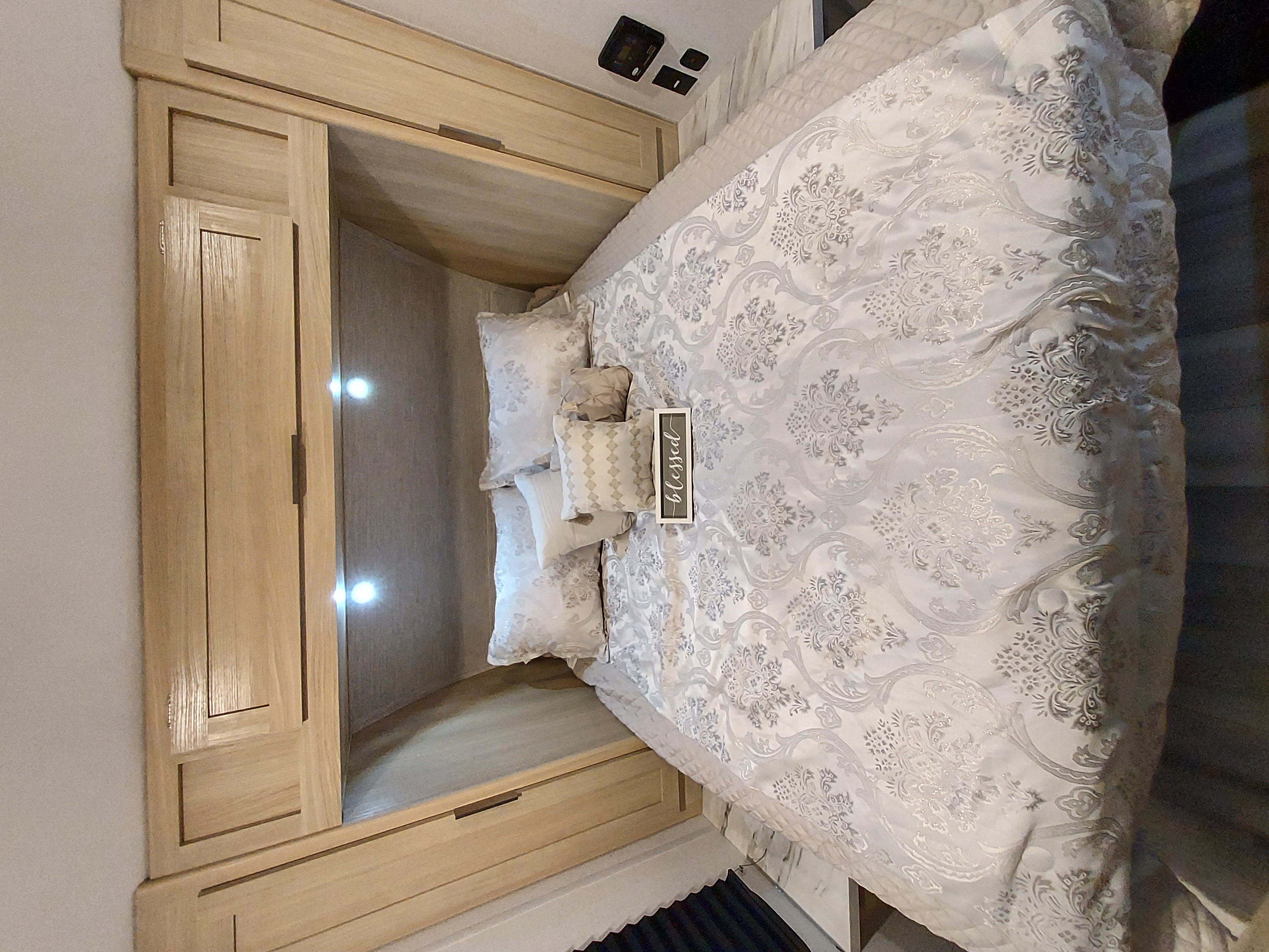 Cozy RV rental bedroom with elegant patterned bedding, built-in wood cabinets, and accent lighting for a comfortable stay.. Forest River Salem FSX Platinum 2023