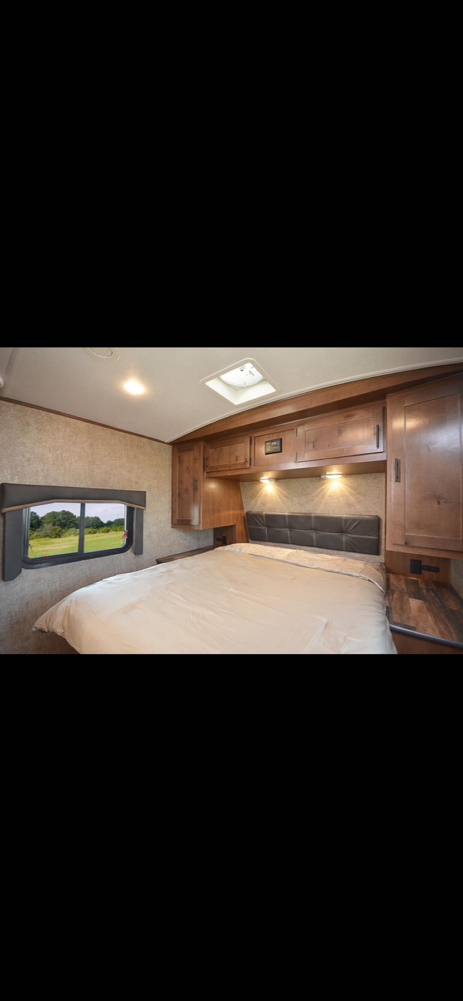 Experience comfort in this RV rental bedroom. Features a comfy bed, ample storage, and a scenic window, perfect for your next trip.. Outdoors Rv Manufacturing Black Stone 2023