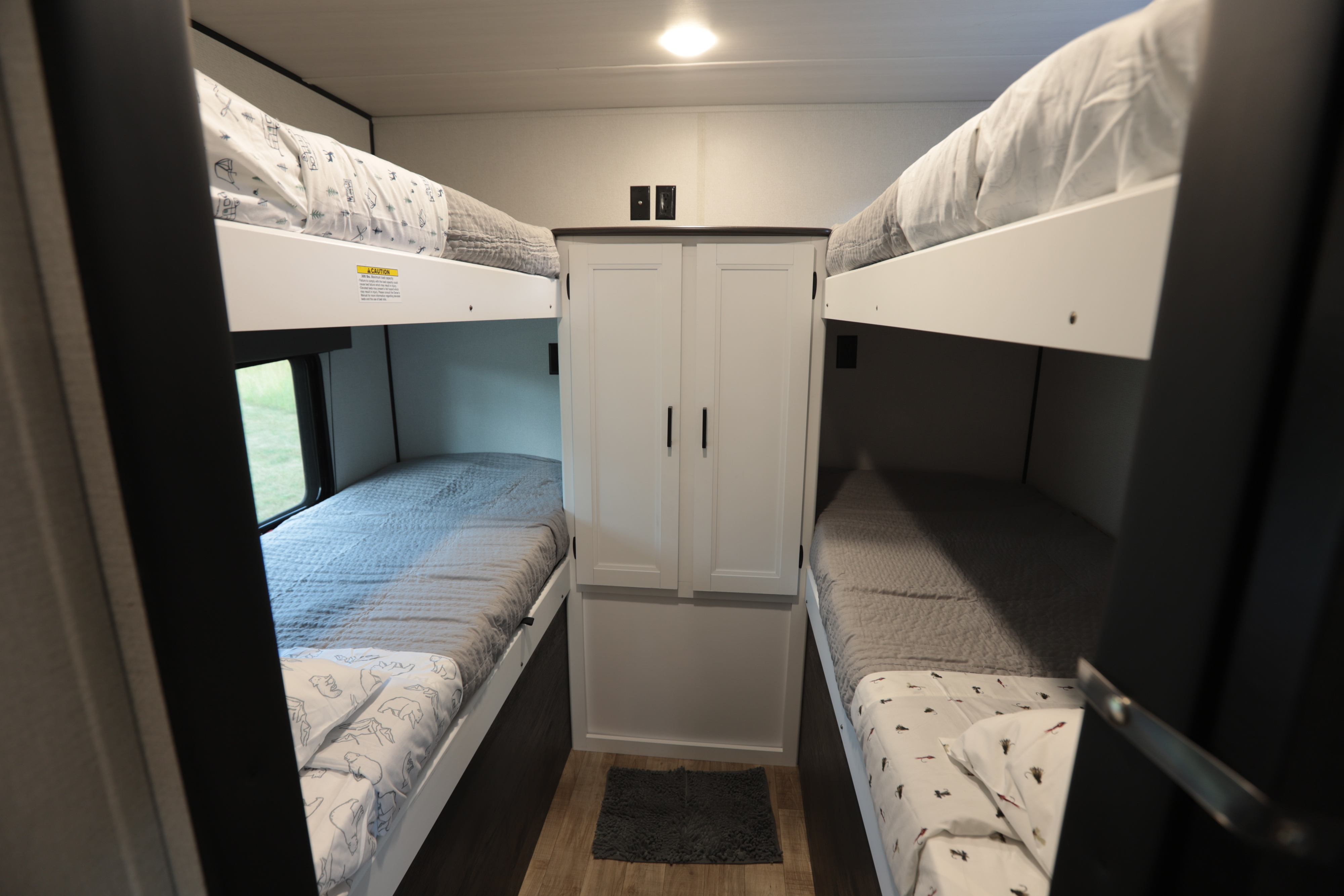 Inside an RV rental: cozy bunk beds with different bedding designs flank central storage cabinets. Perfect for families.. Keystone RV Hideout 2022